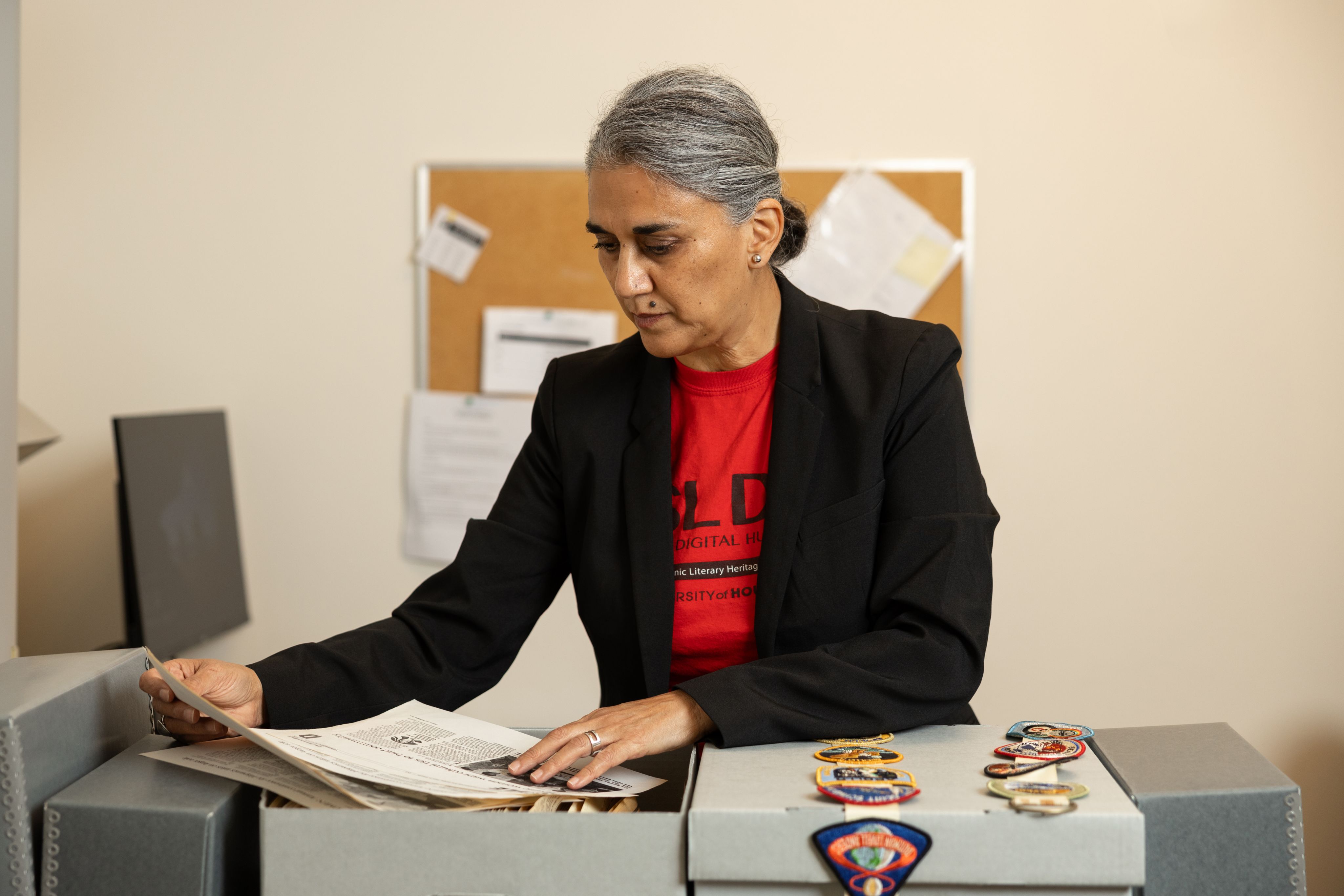 Dr. Gabriela Baeza Ventura sits at her desk looking at archival material for Recovering the U.S. Hispanic Literary Heritage.