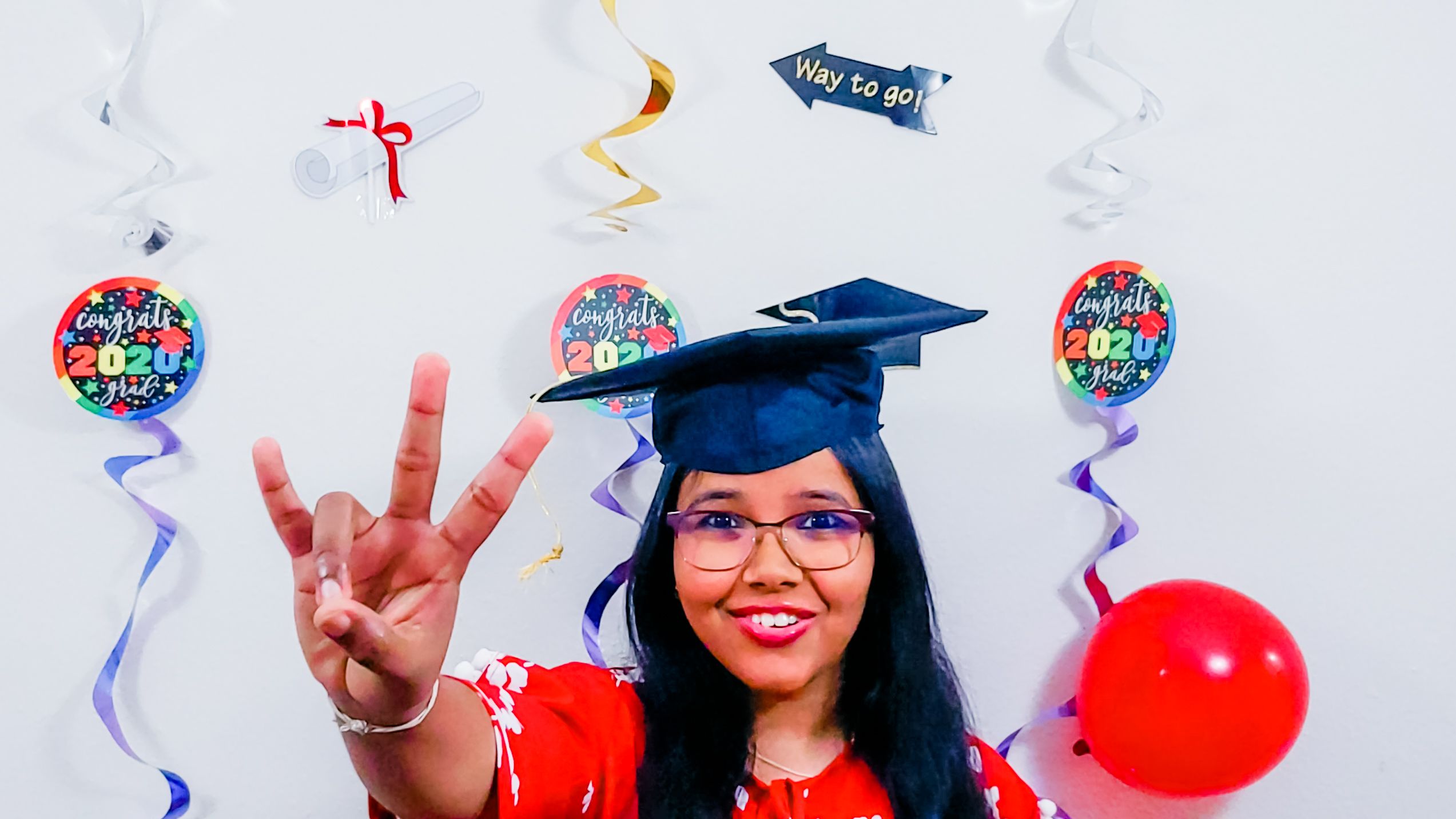 Female grad wearing mortar board graduation cap holding up Go Coogs handling