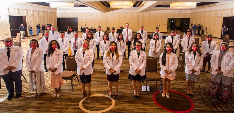 Inaugural College of Medicine Class Photo- 30 students wearing white coats and distanced