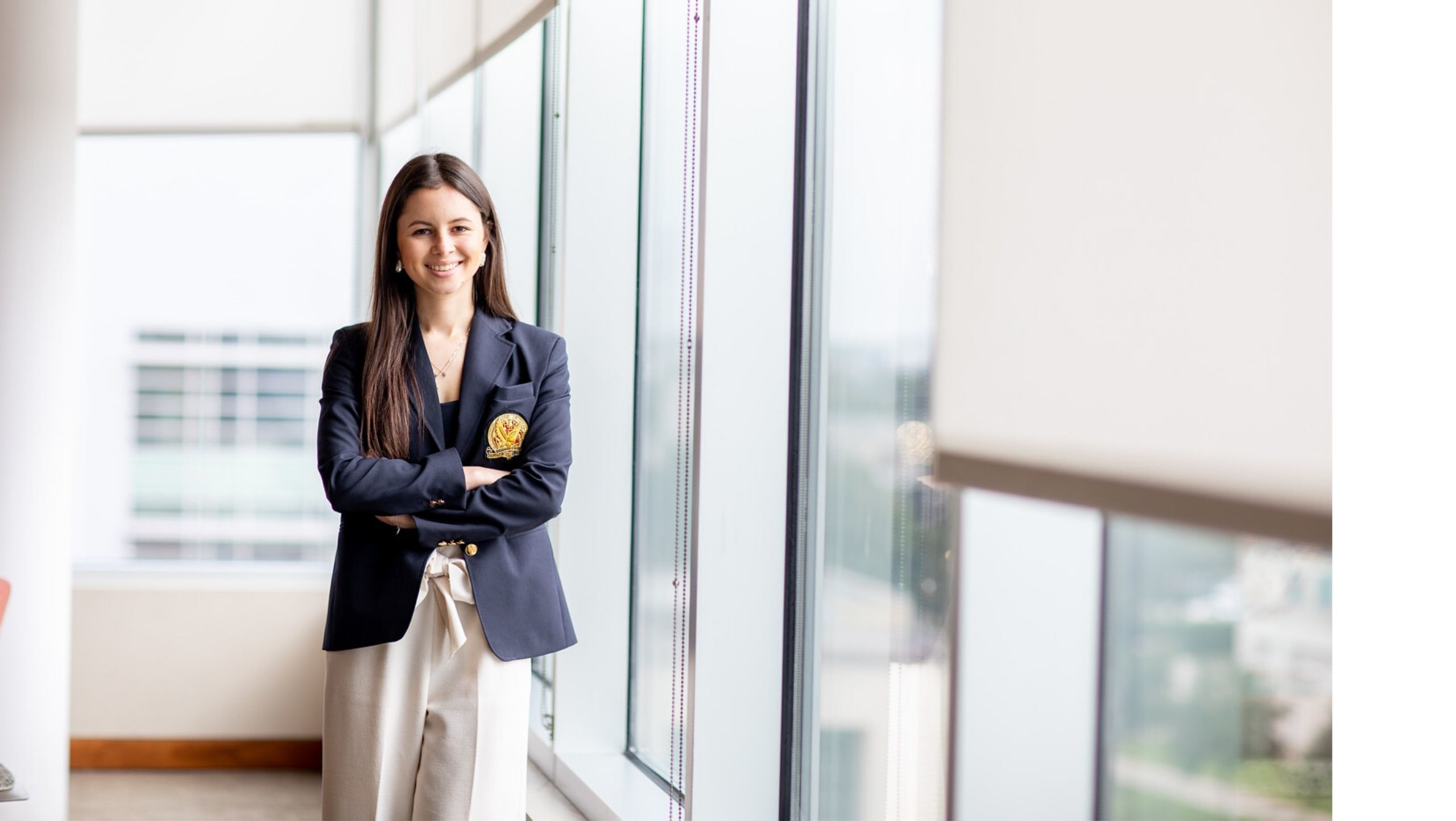 Woman in Wolff Center blazer, poses in hallway