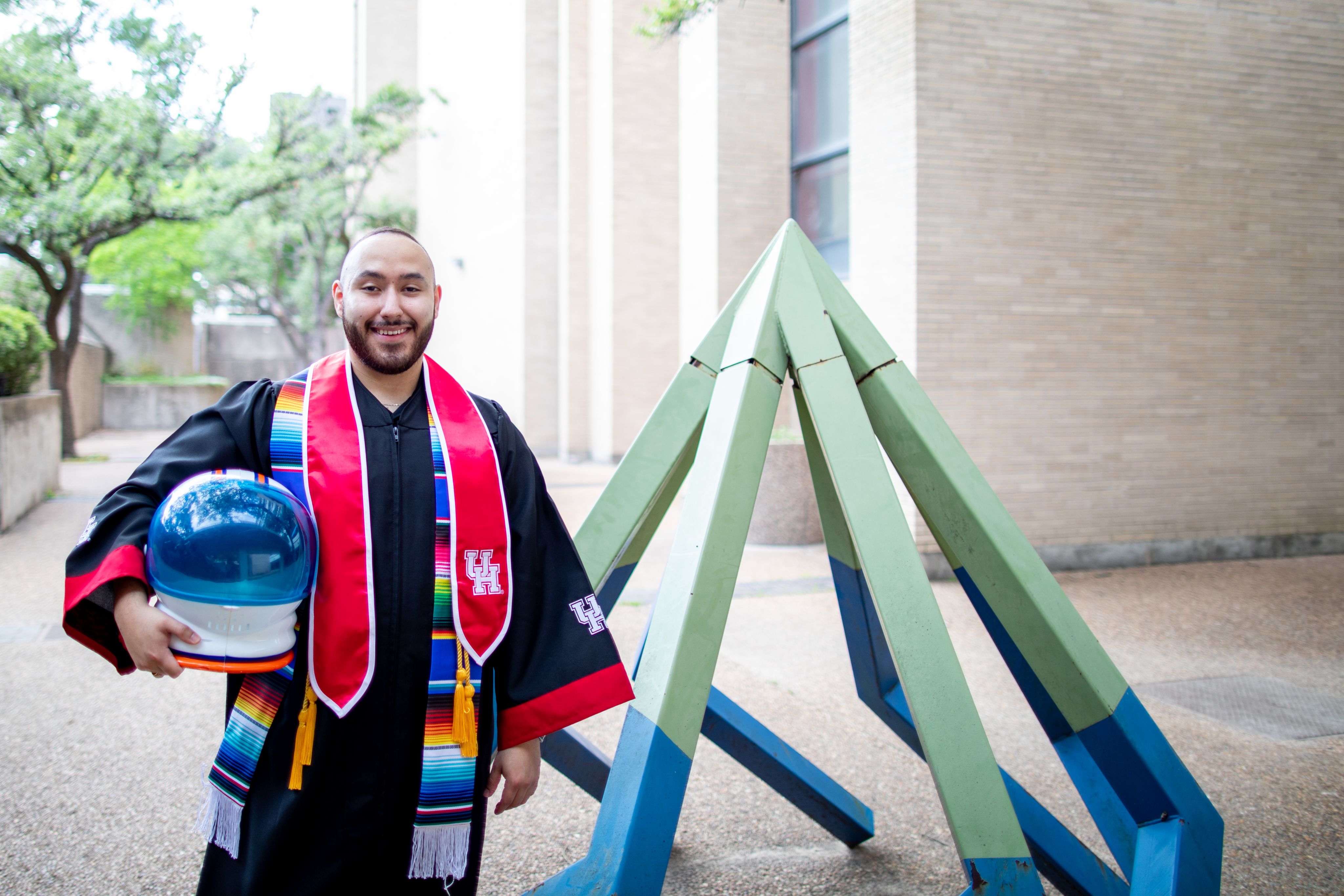 Heriberto Triana poses in graduation regalia for photos.