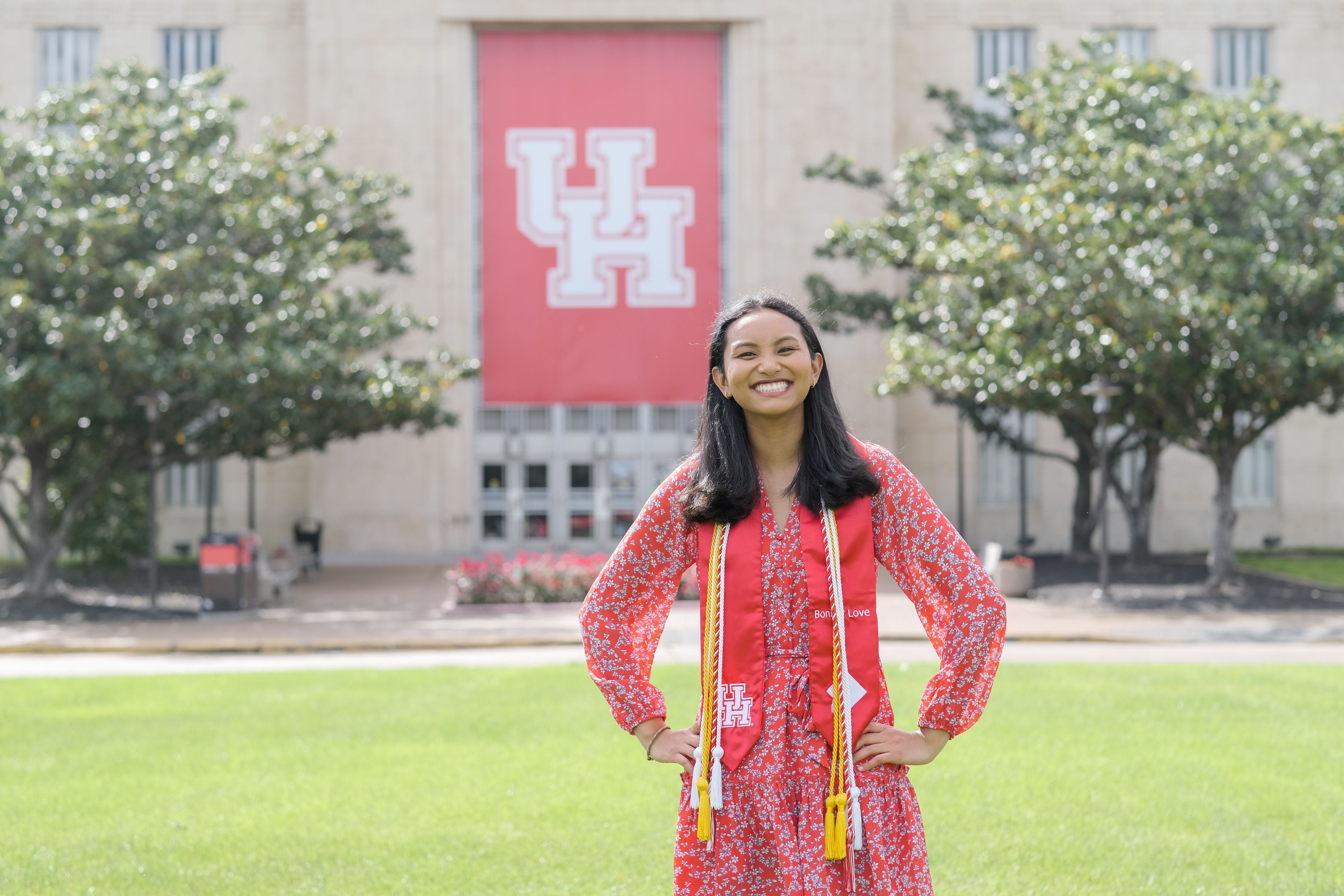 student with red dress in front of building