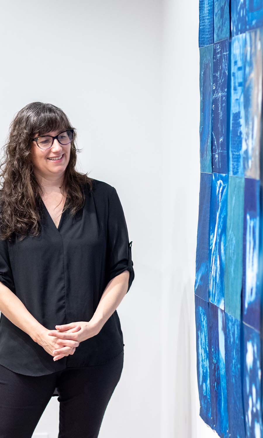 Anderson-Staley stands next to one of her pieces that hangs on the gallery wall in her exhibition.