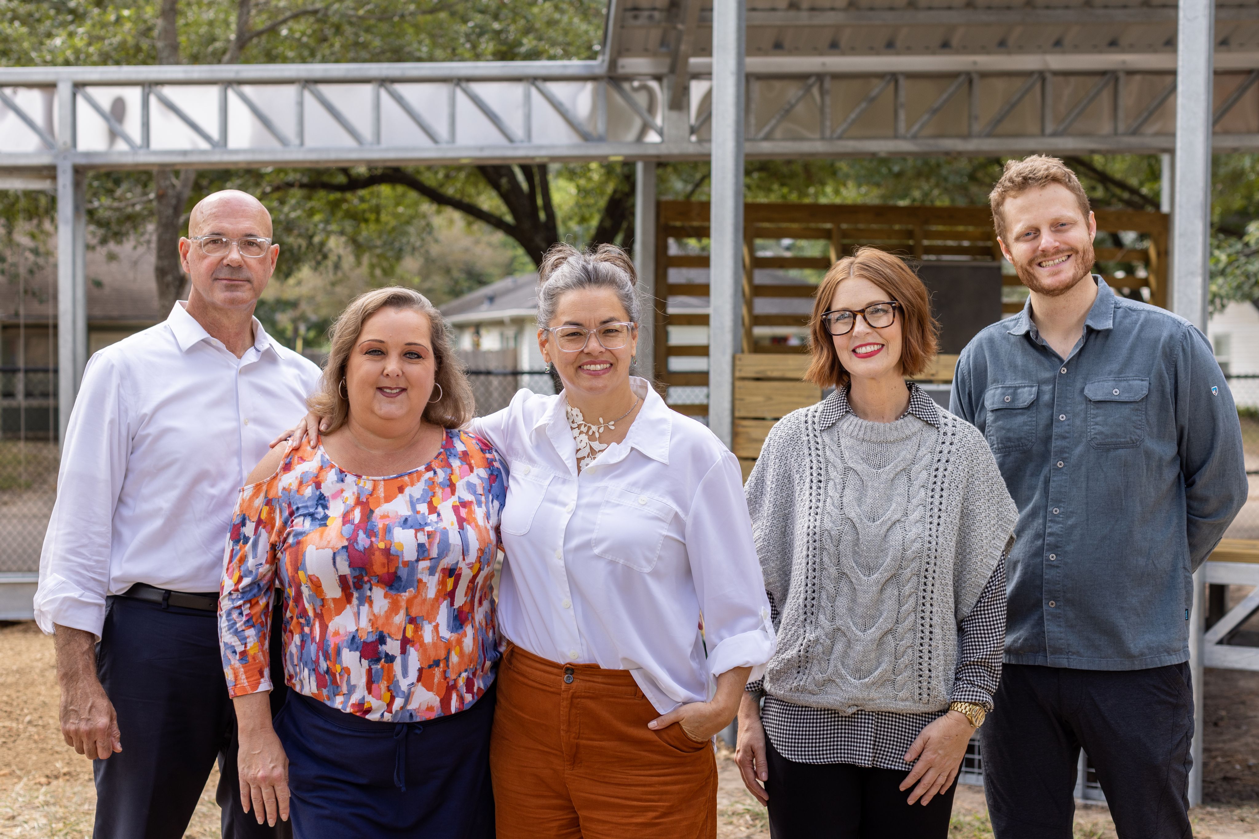 Five adult persons posing for a group photo.