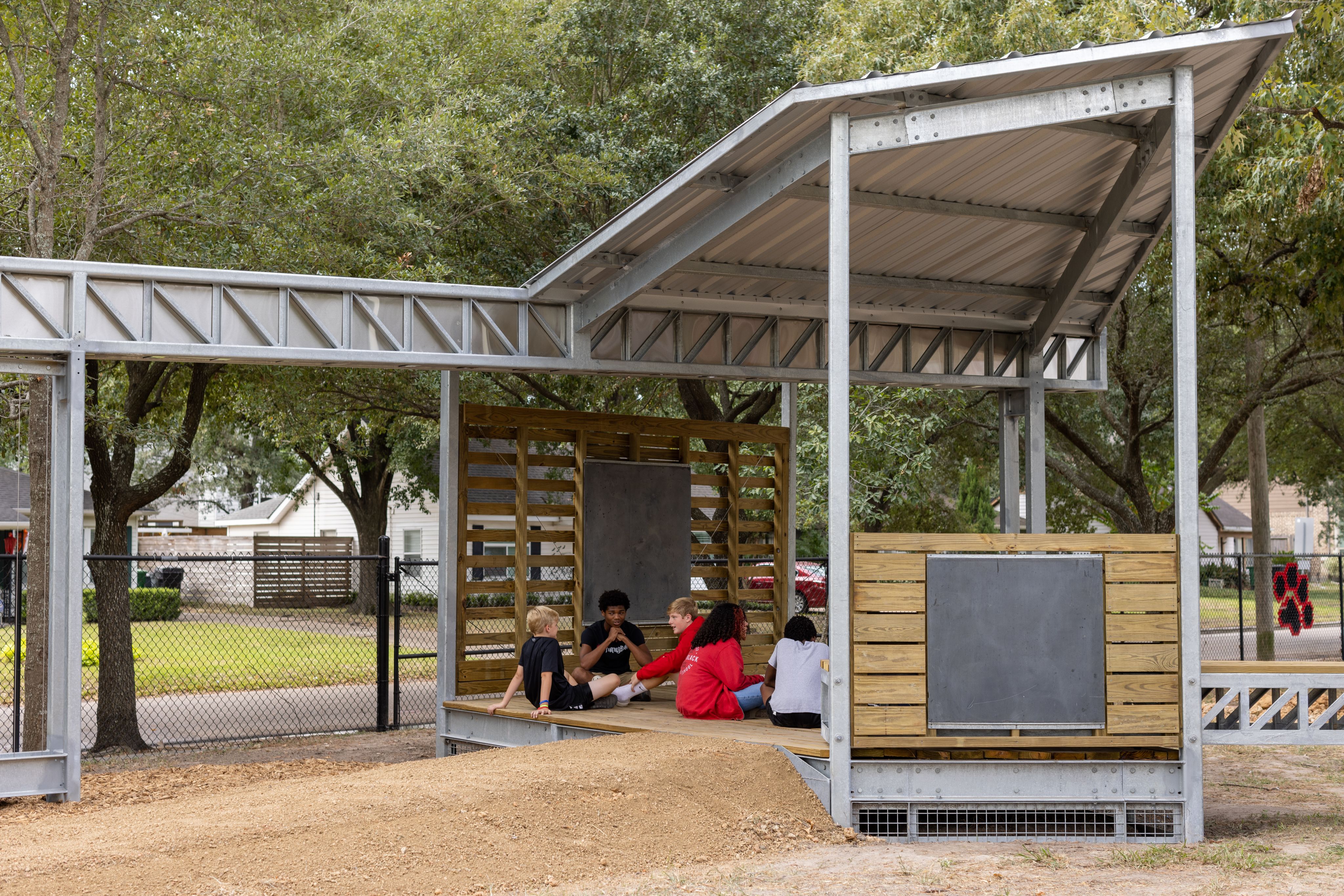 Children sitting in a structure that is used as an outdoor classroom.