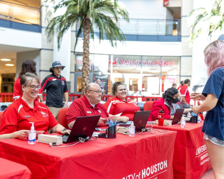 Residential Life staff at tables help students check in to their new homes for the school year in rotunda of campus rec center.