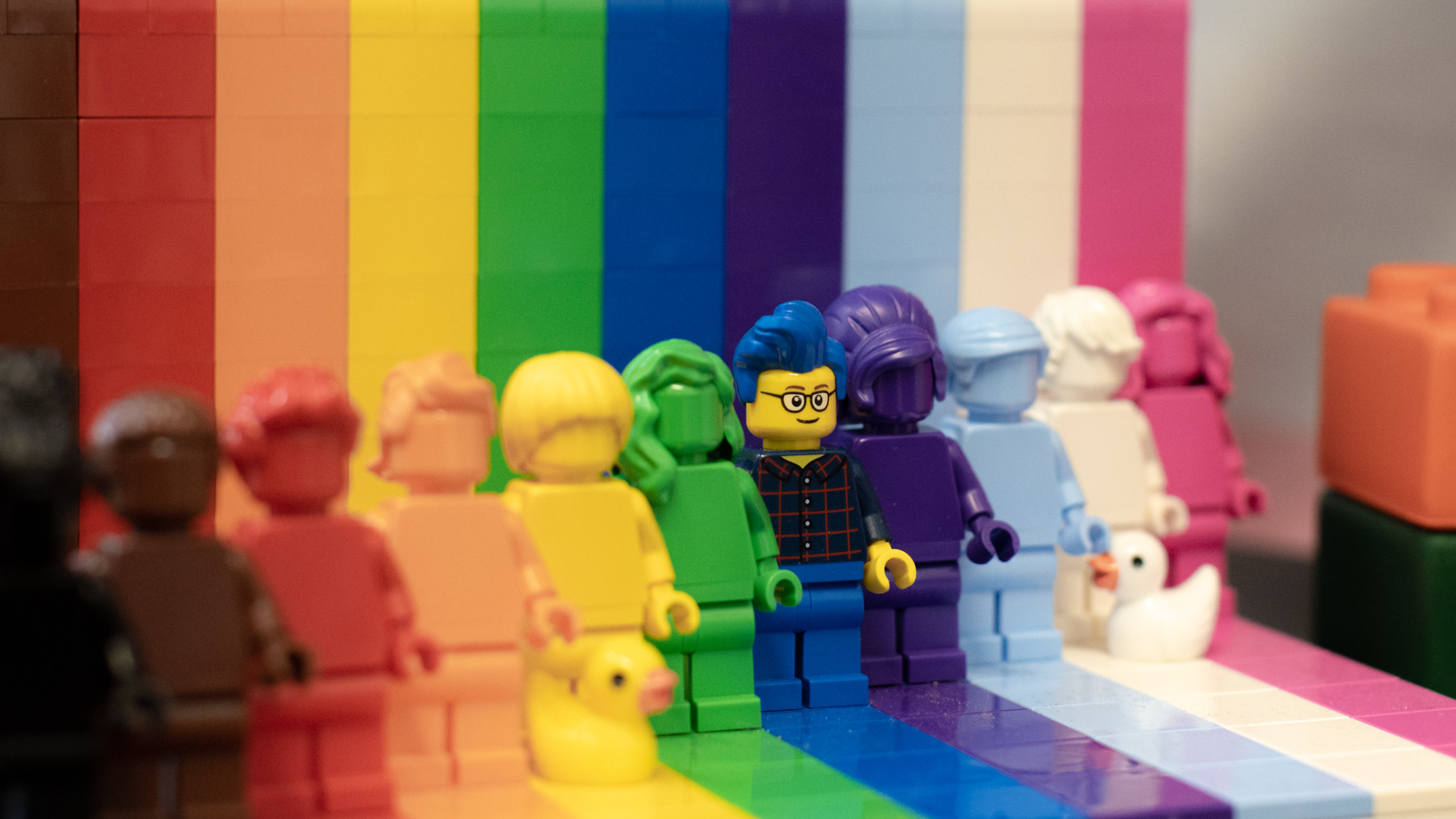 Lego figures in all colors of the rainbow, lined side by side