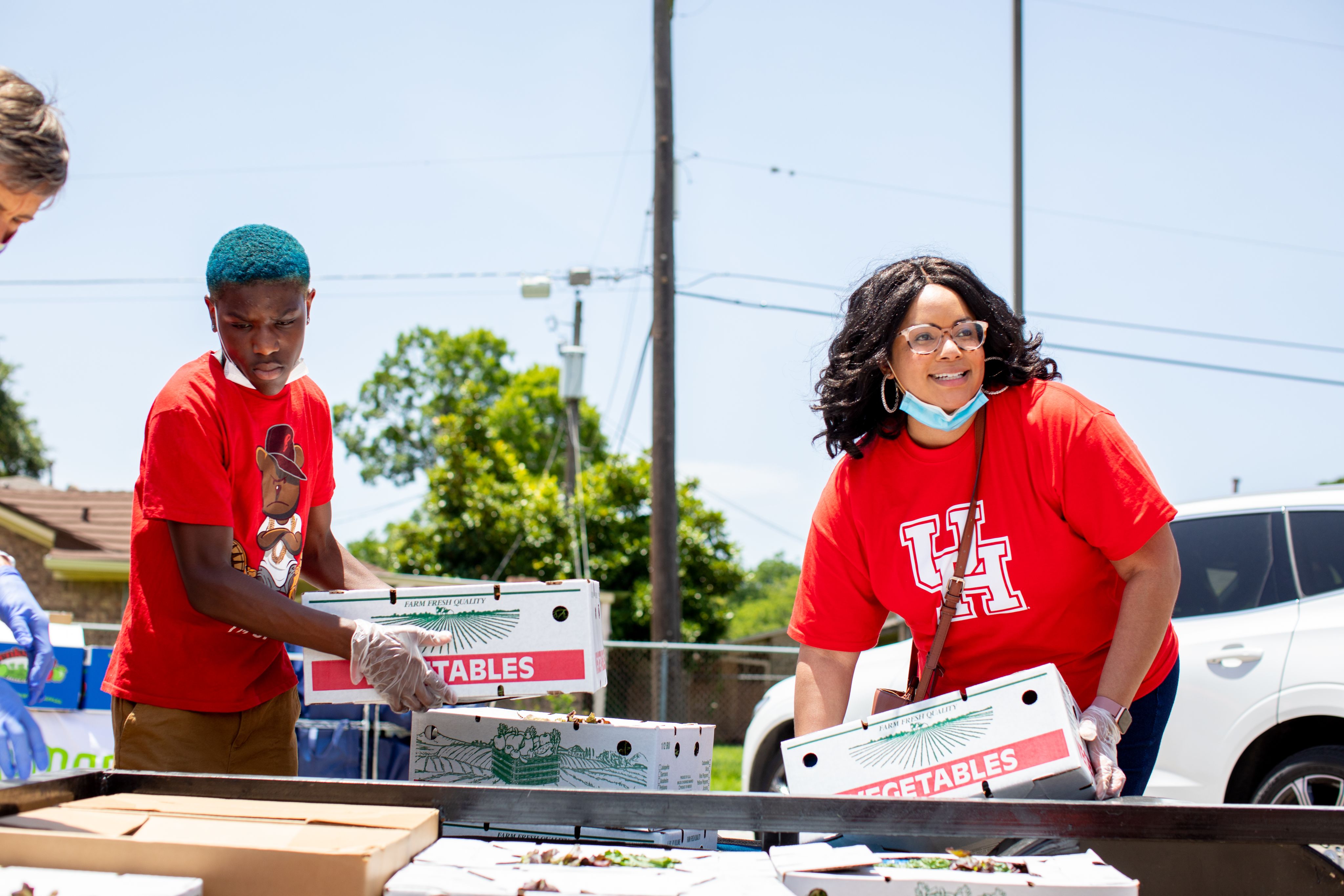 Medical school staff member holding box of vegetables at volunteer event