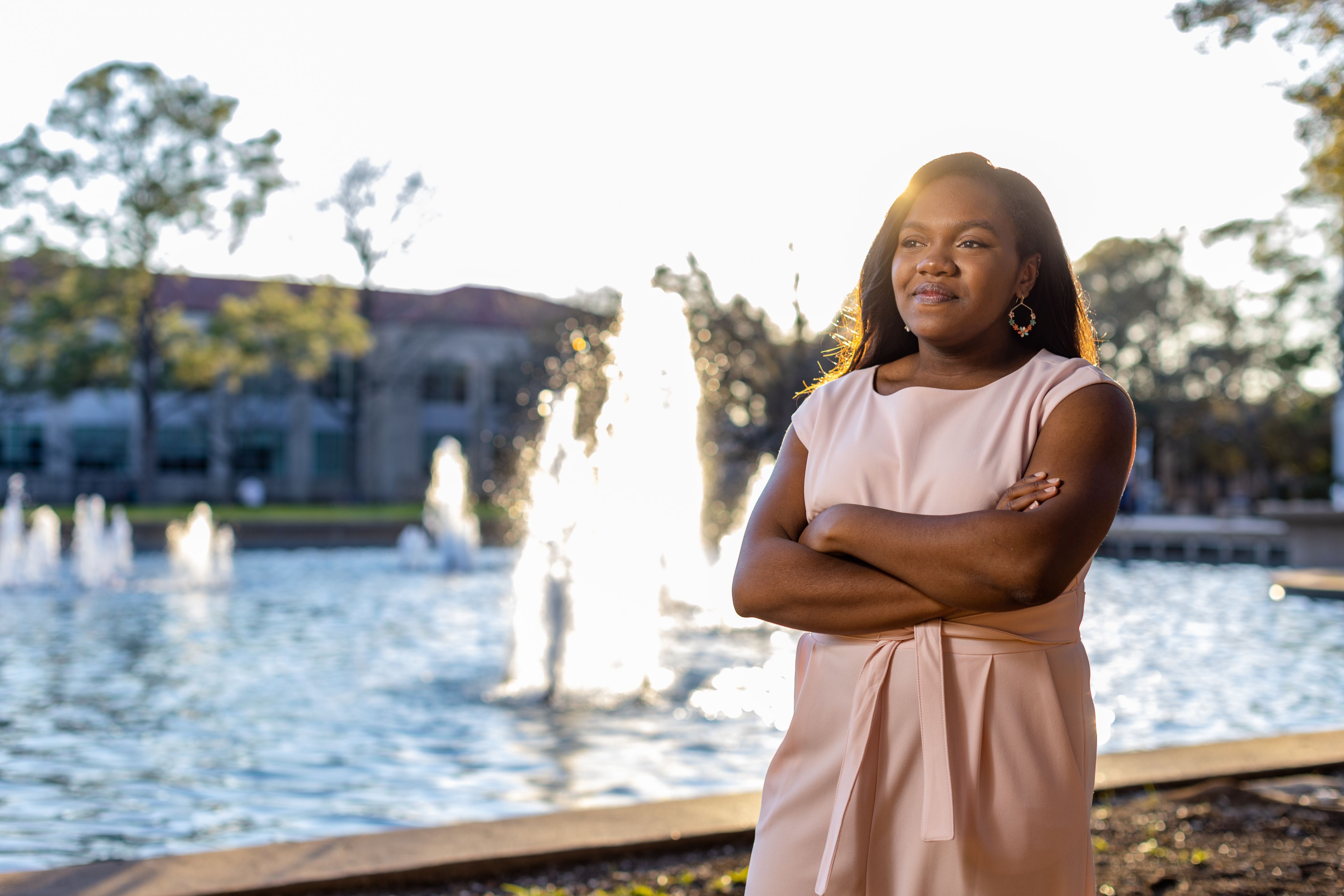African American woman with arms folded, standing by fountain