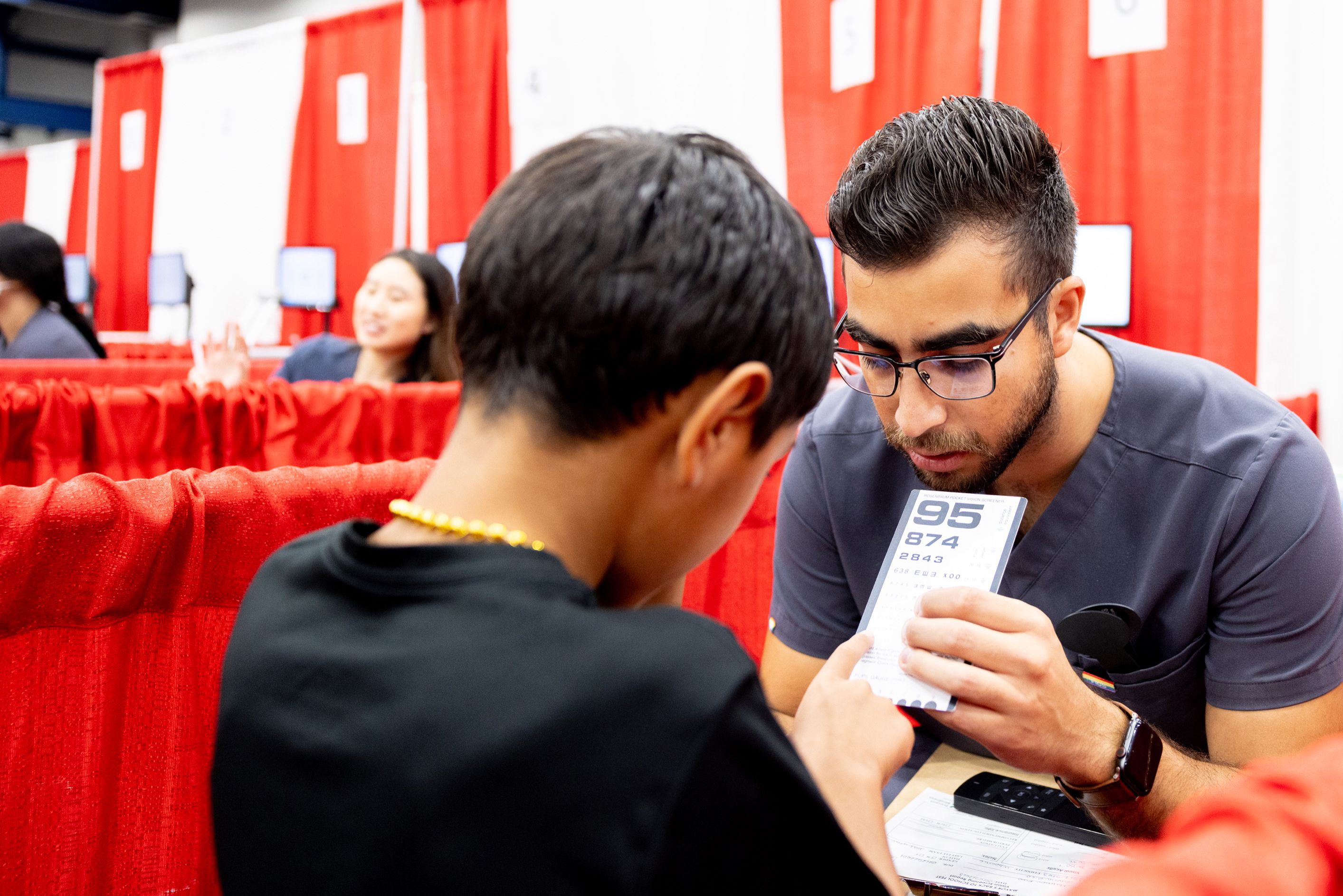 Adrian Velasco, a fourth-year optometry student, provides a vision screening at the Mayor's Back to School Fest.
