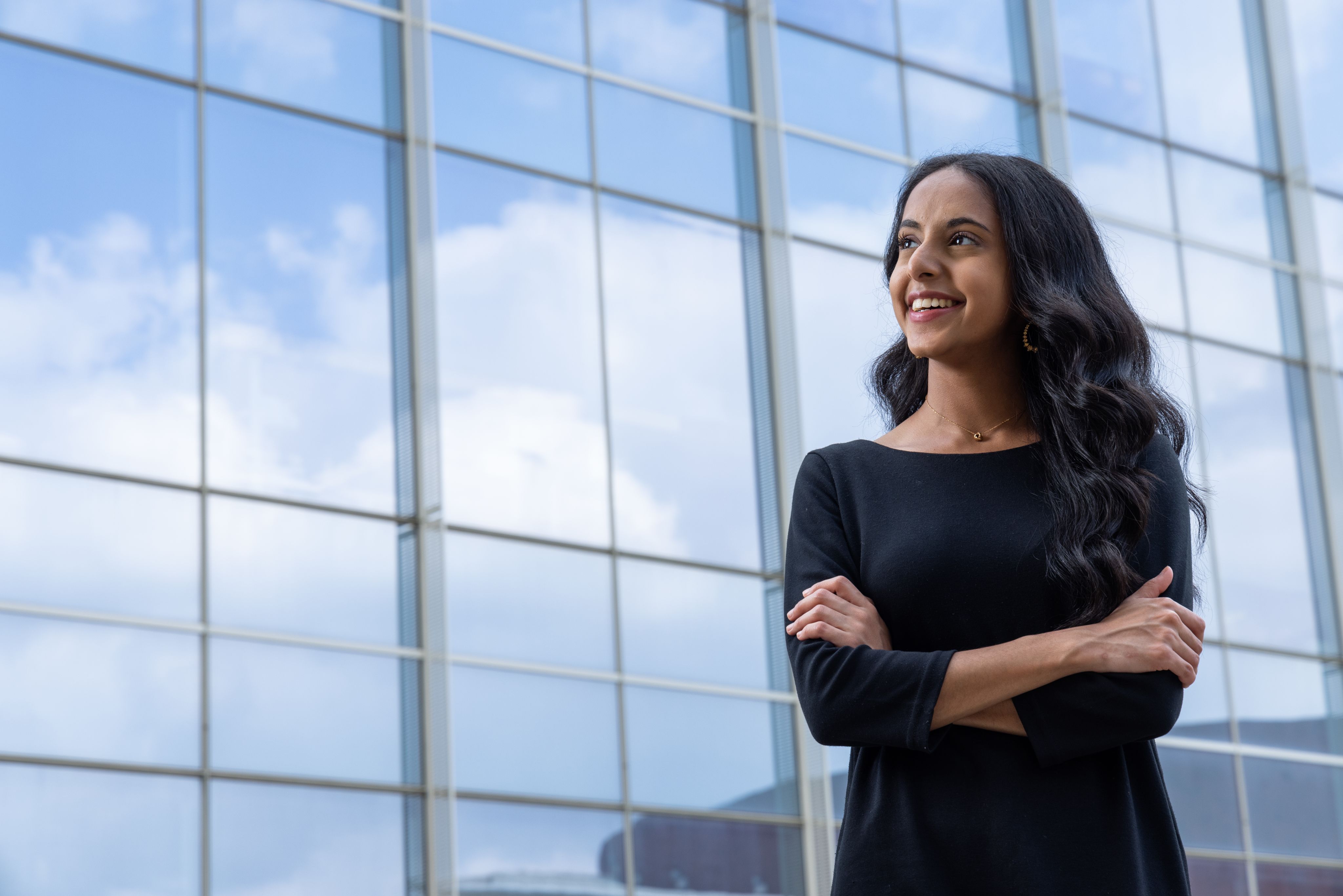 Diya Patel looking to the left and smiling with arms crossed.