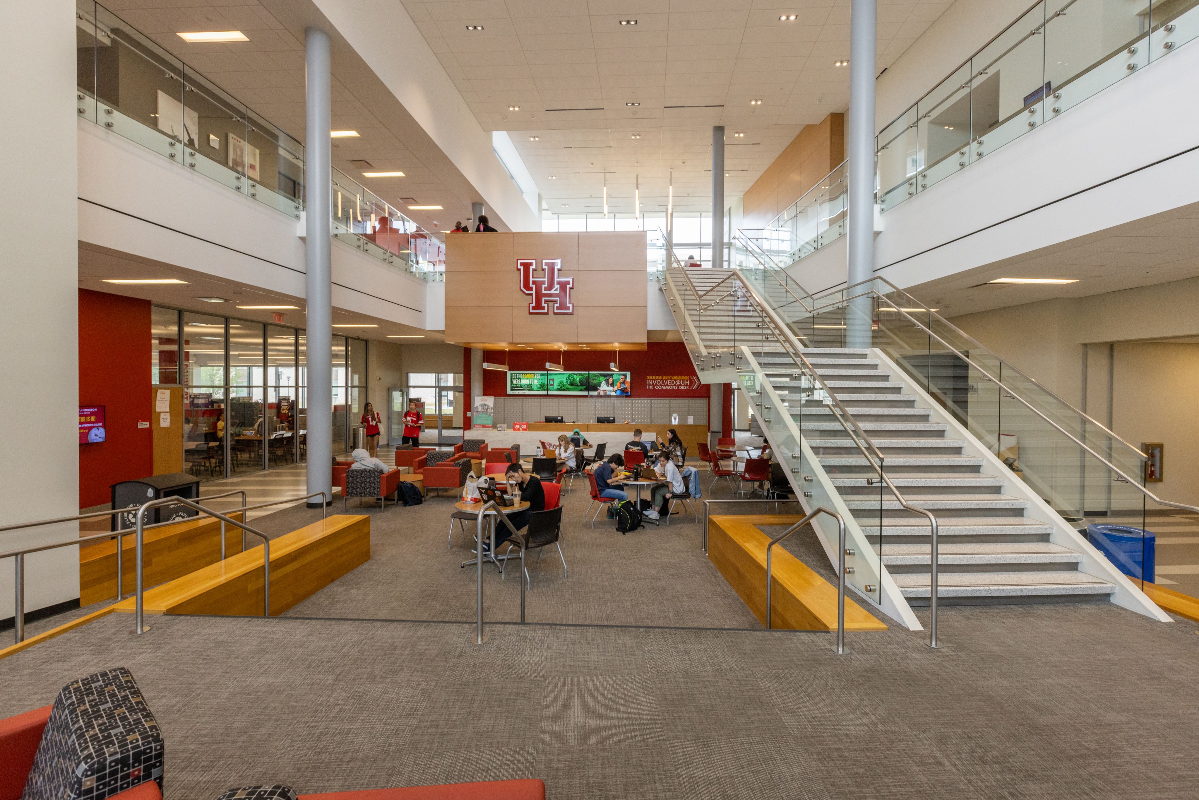Interior of Student Center North at UH. A group of tables and chairs are on the left, with a large staircase on the right that leads to the second floor.