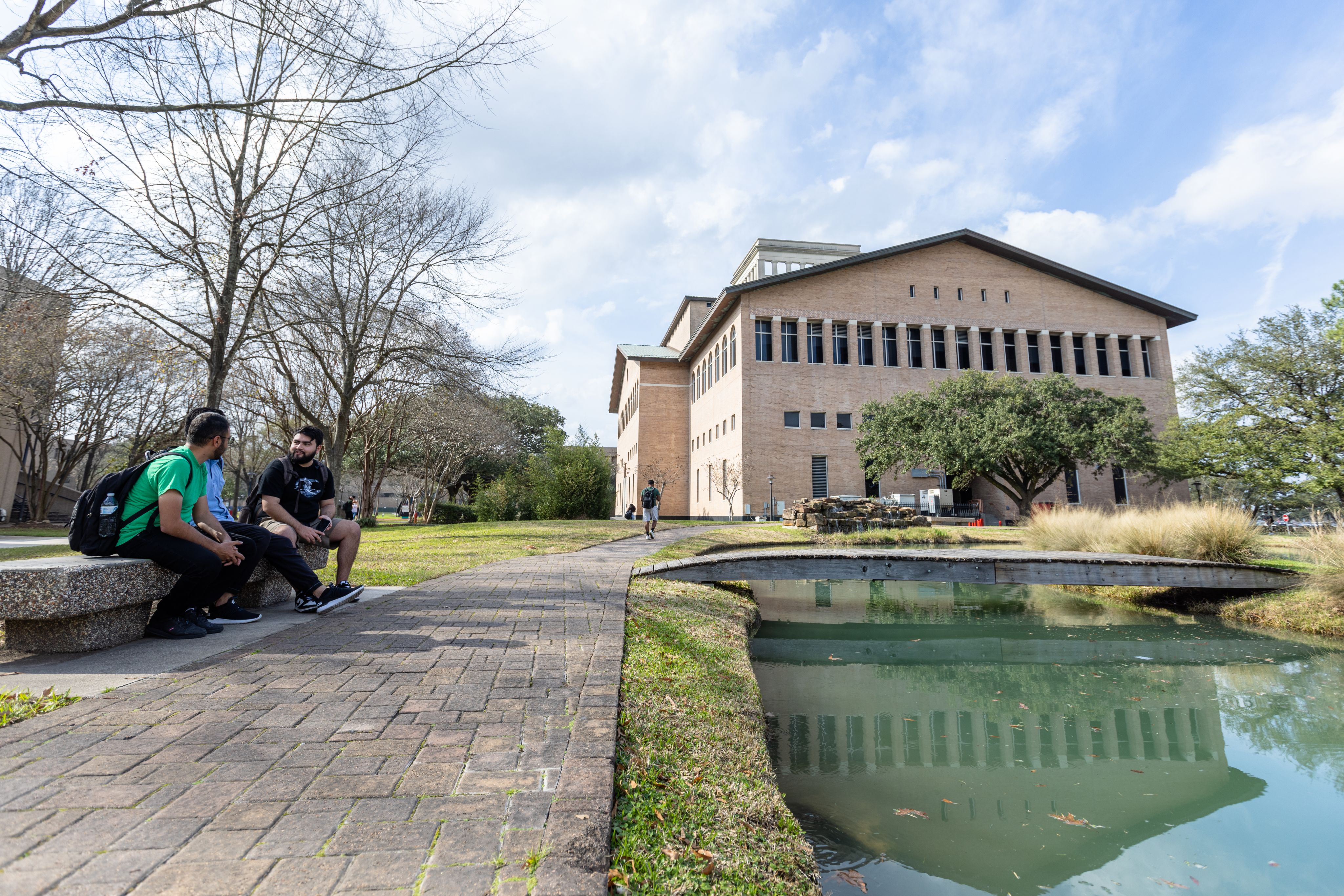 Outdoor koi pond near the Architecture building. A wooden bridge crosses over to a small man-made island in the center of the pond.