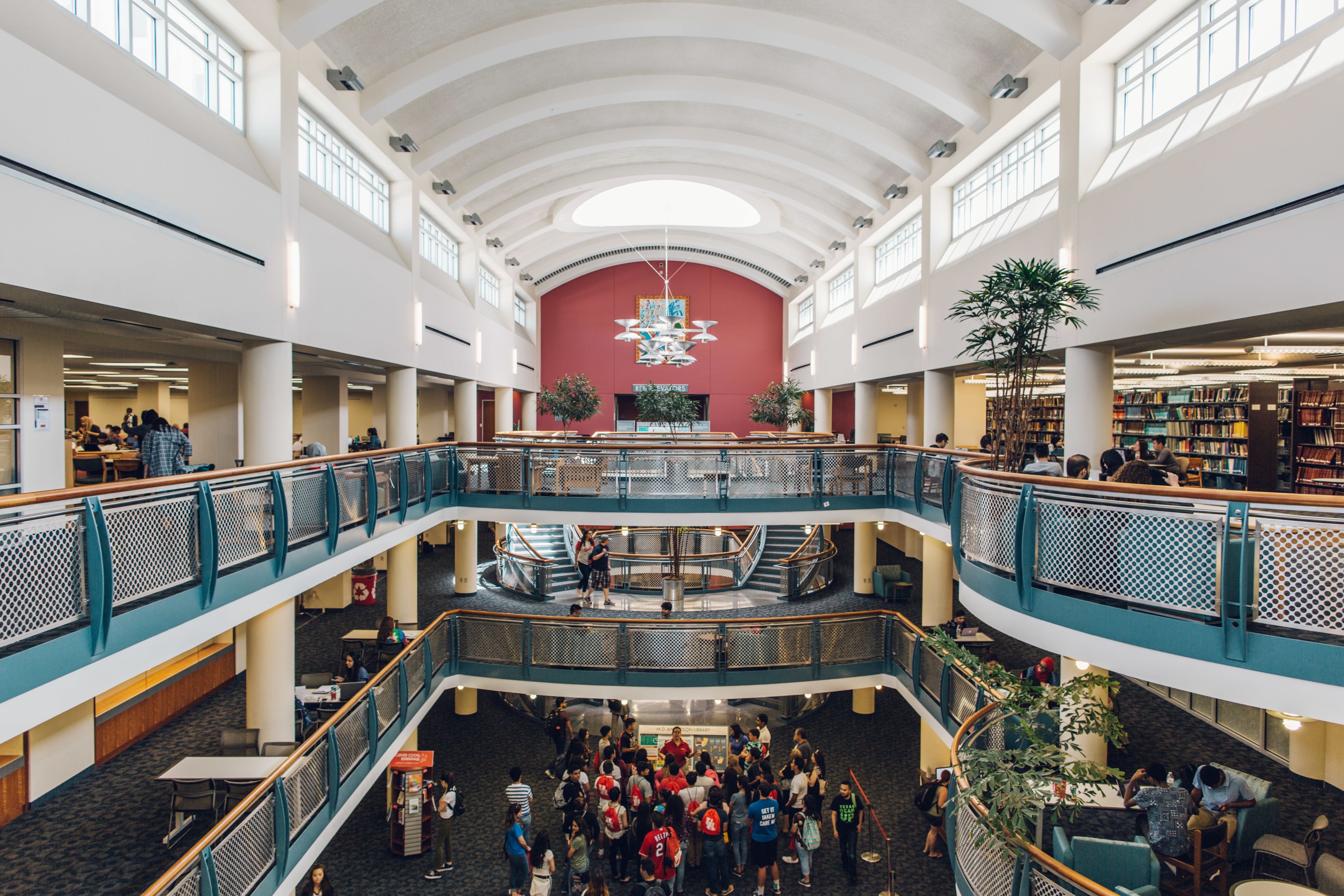 Interior view of the M.D. Anderson Library looking over a balcony. Several potted trees can be seen, with natural light filling the space.