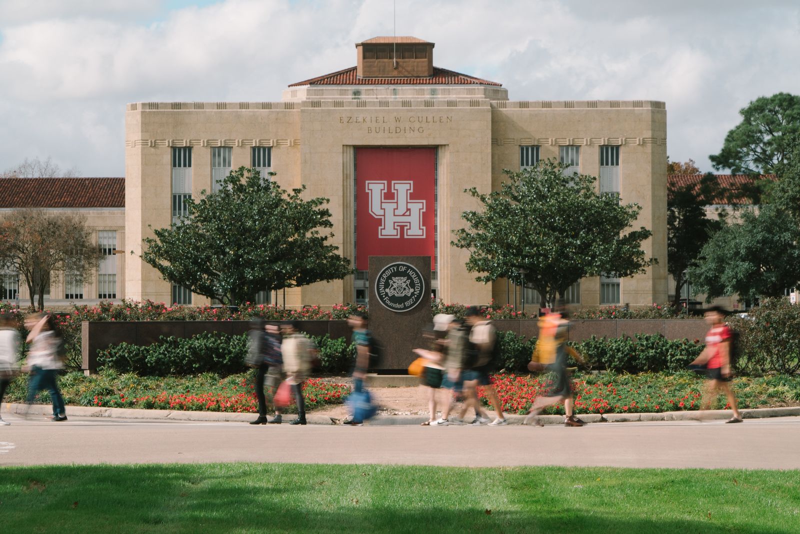 Several students walking quickly in front of E. Cullen building