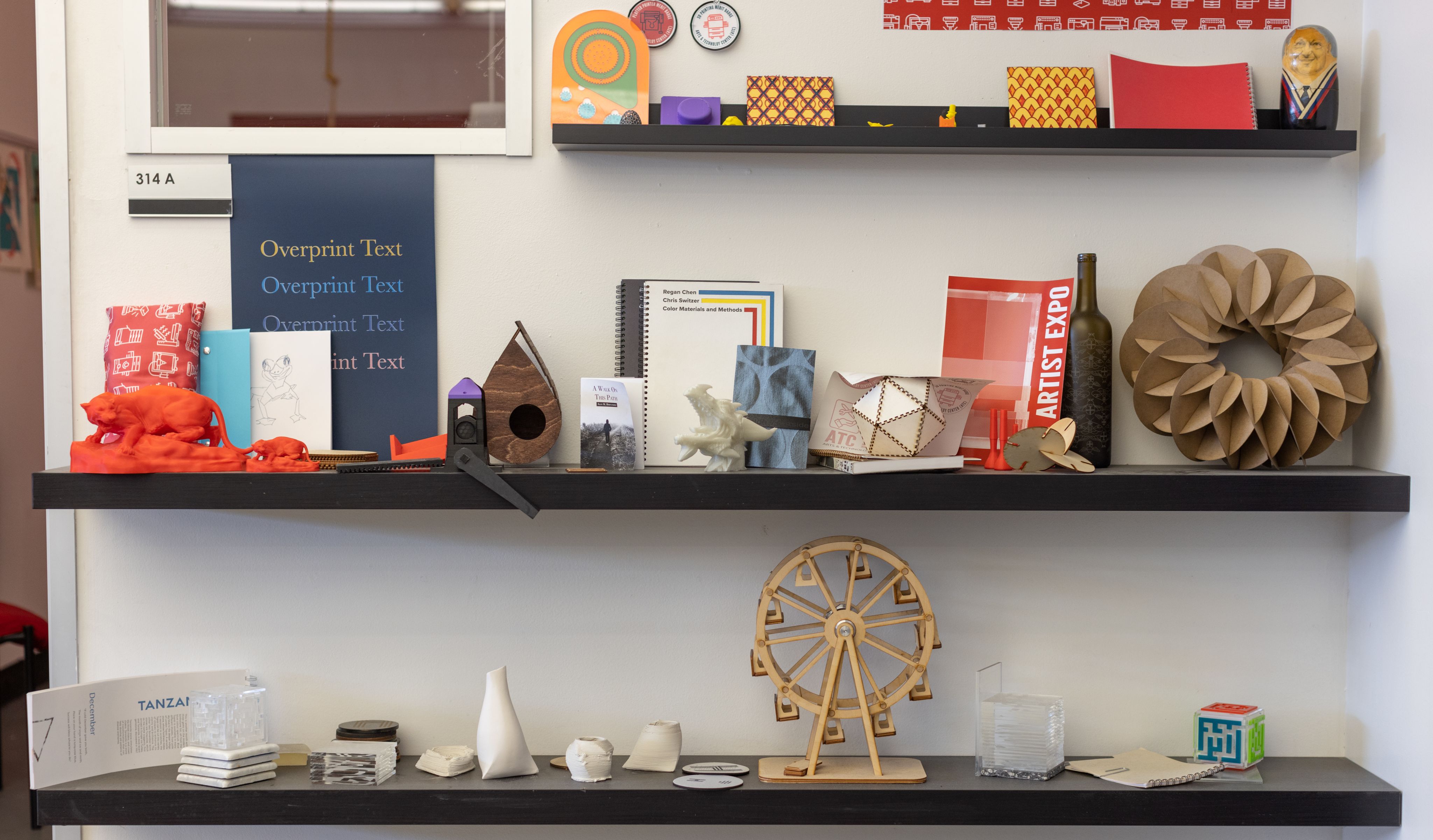 Photo of shelves of art projects ranging from 3d printed objects to books.