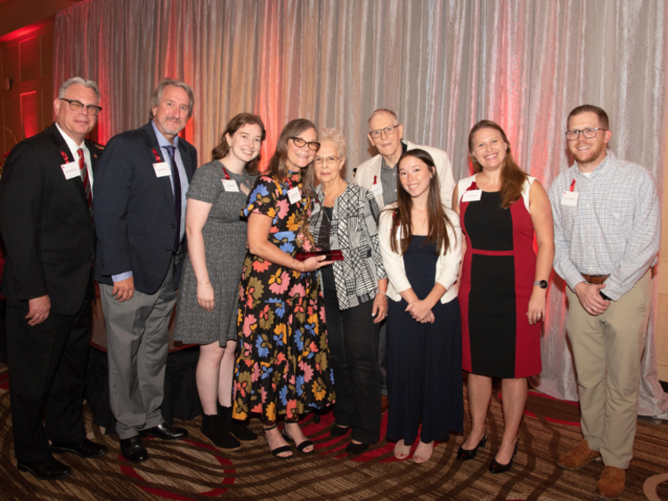 2023 C.F. McElhinney Distinguished Service Award winner Ginger Walker (center) holding her crystal trophy and her family gathered together with Raymond Bartlett, Vice President for Administration and Finance (far left).