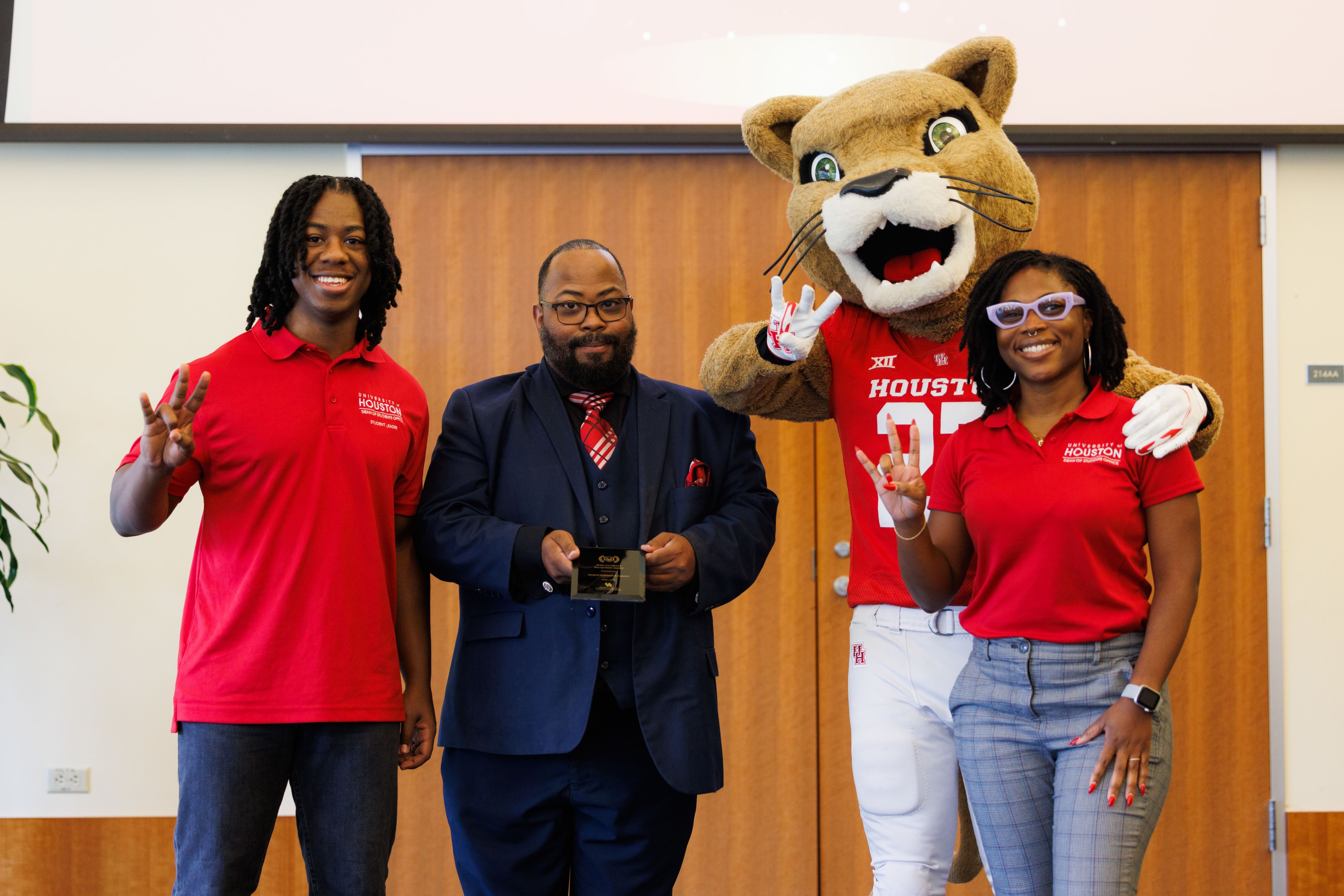 Staff Council President Karl A. Hearne and UH Mascot Shasta posing with Team Excellence award winners Michael Campbell (left) and Gabreille Miller (right).