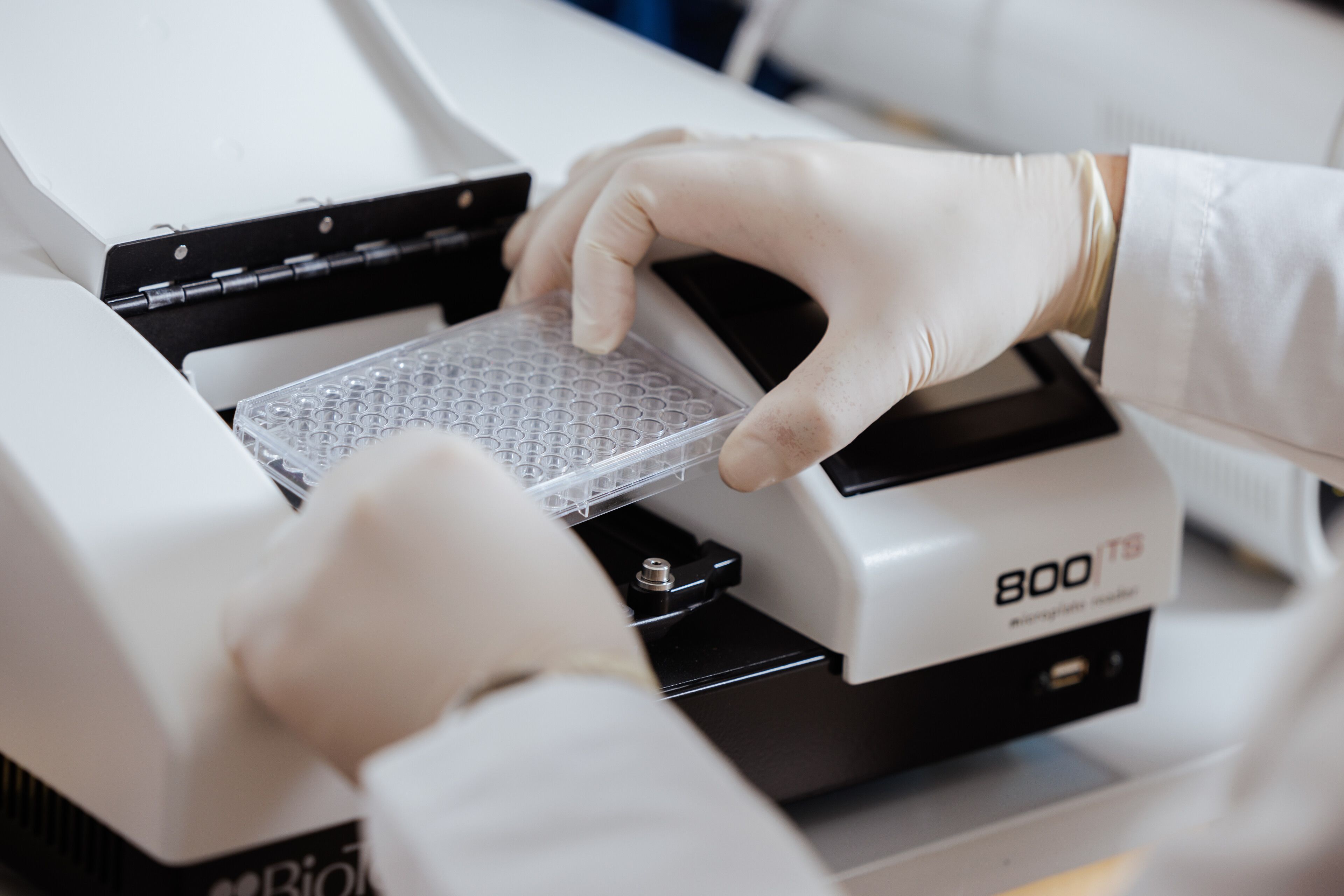 A person in a lab coat operates a machine, demonstrating a scientific or technical process in a laboratory setting.
