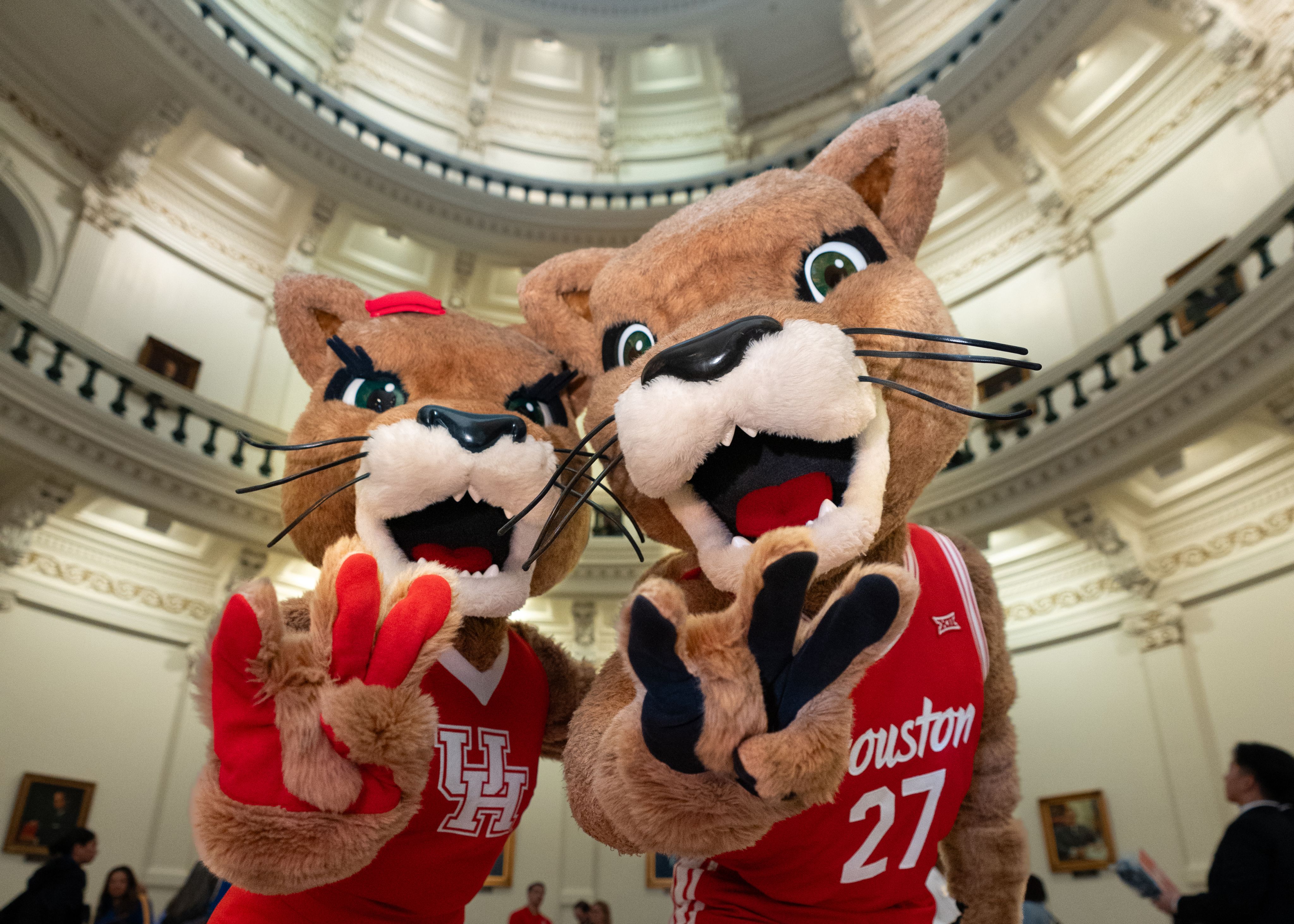 UH mascots showing cougar paws in capitol rotunda.