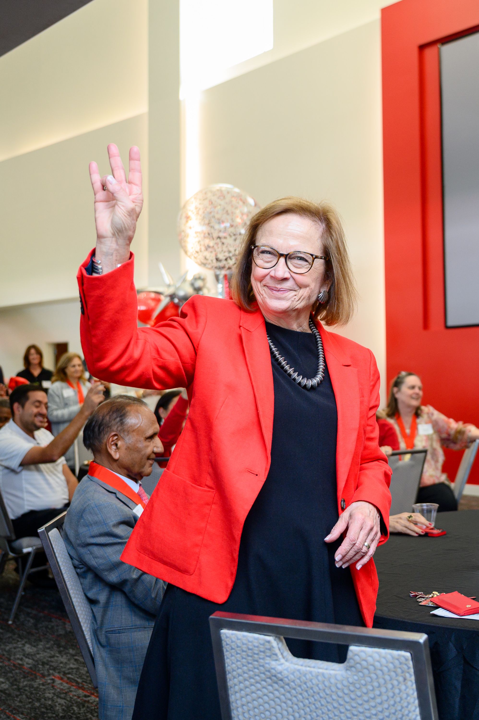 photo of woman wearing red jacket, black shirt and glasses.