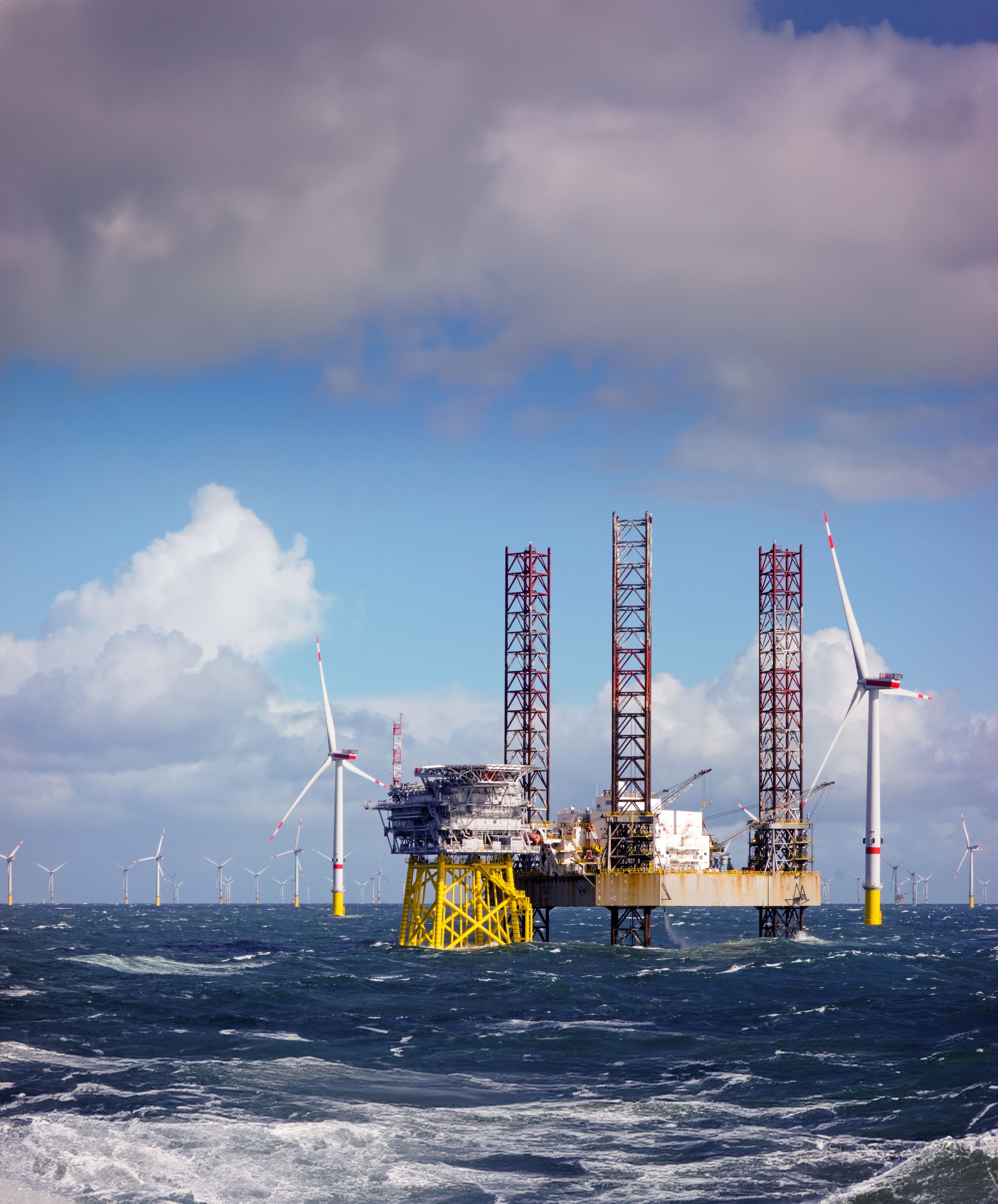 Composite photograph of an offshore oil rig repurposed with wind turbines.