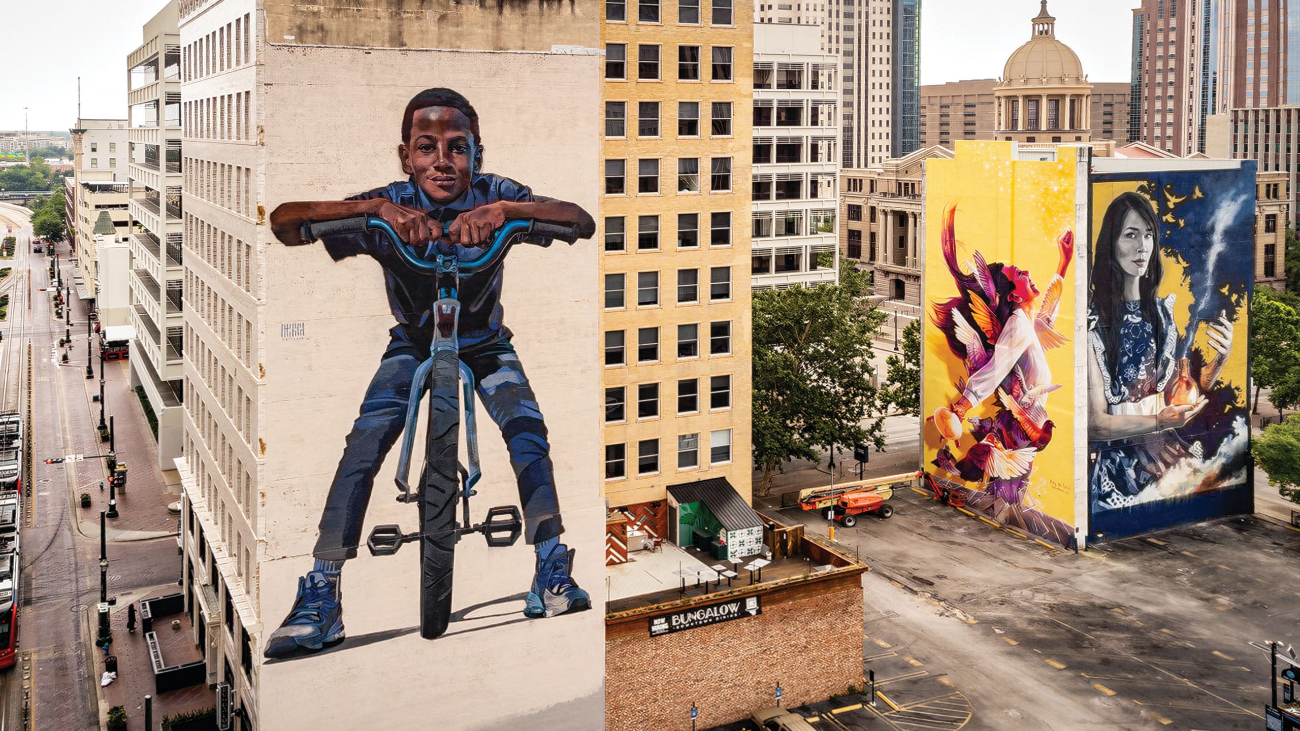 Three large murals painted on buildings in downtown Houston.
