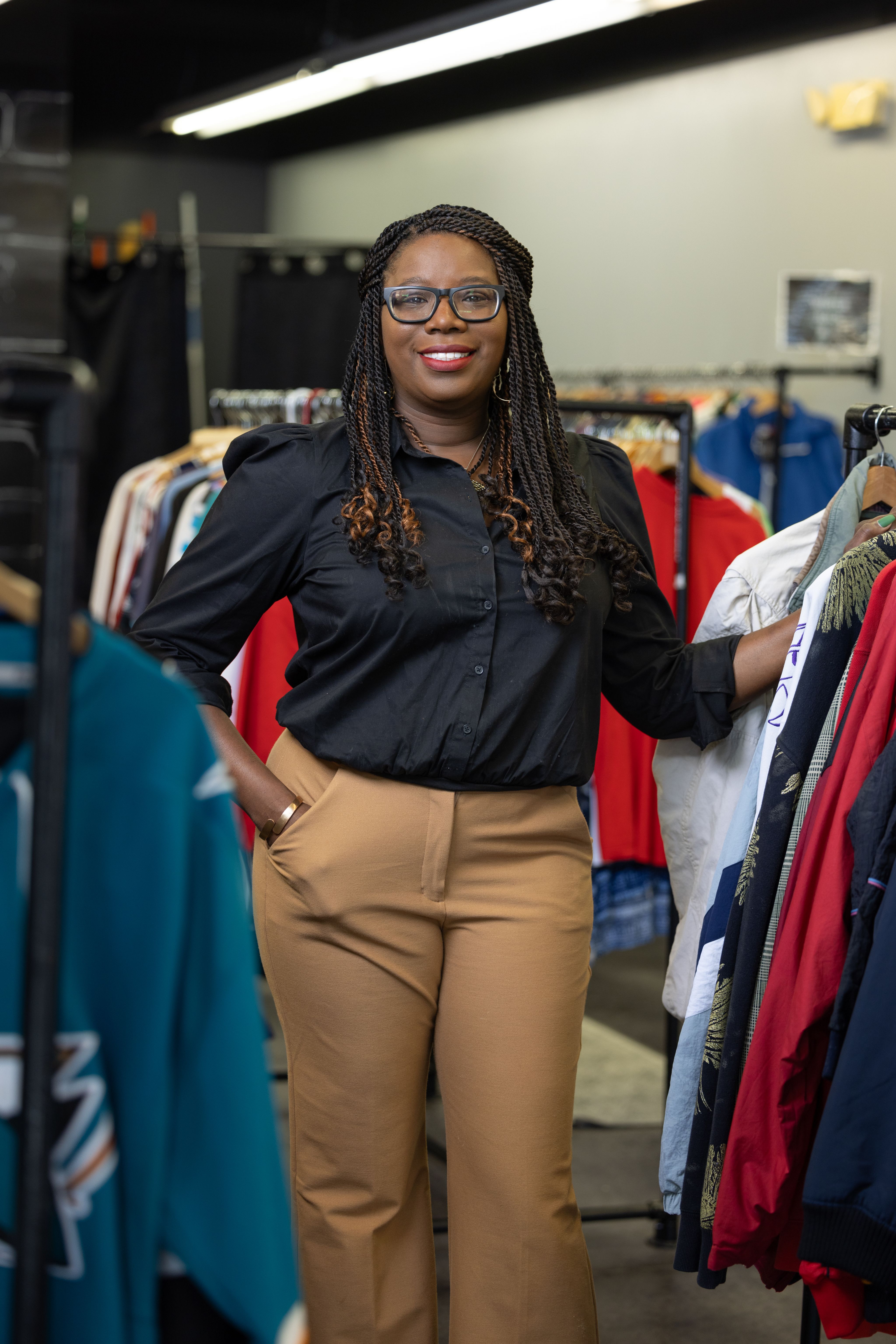 UH Assistant Professor Olivia Johnson standing in between two racks of clothes, smiling at the camera.