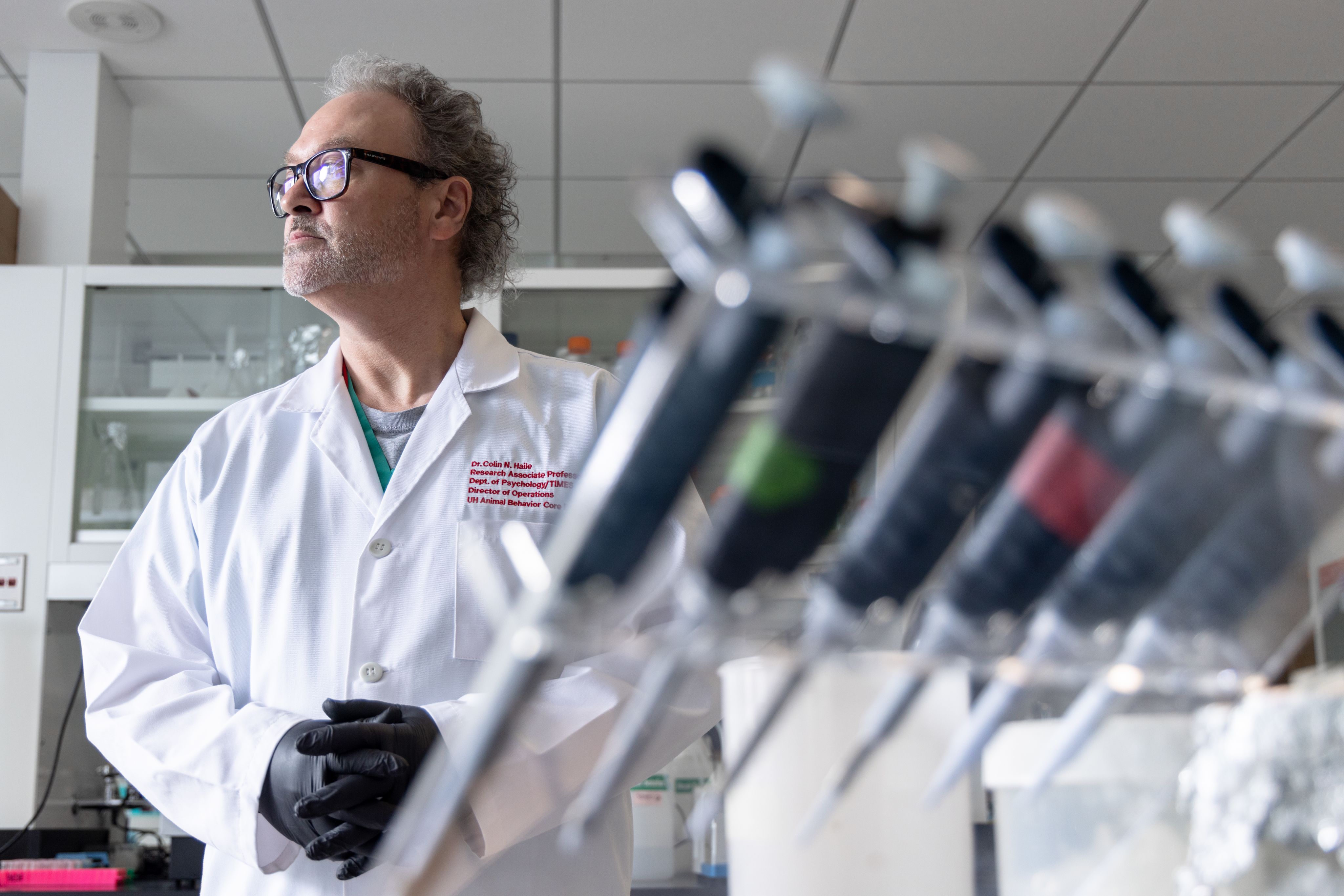 Colin Haile in a lab coat surrounded by lab equipment