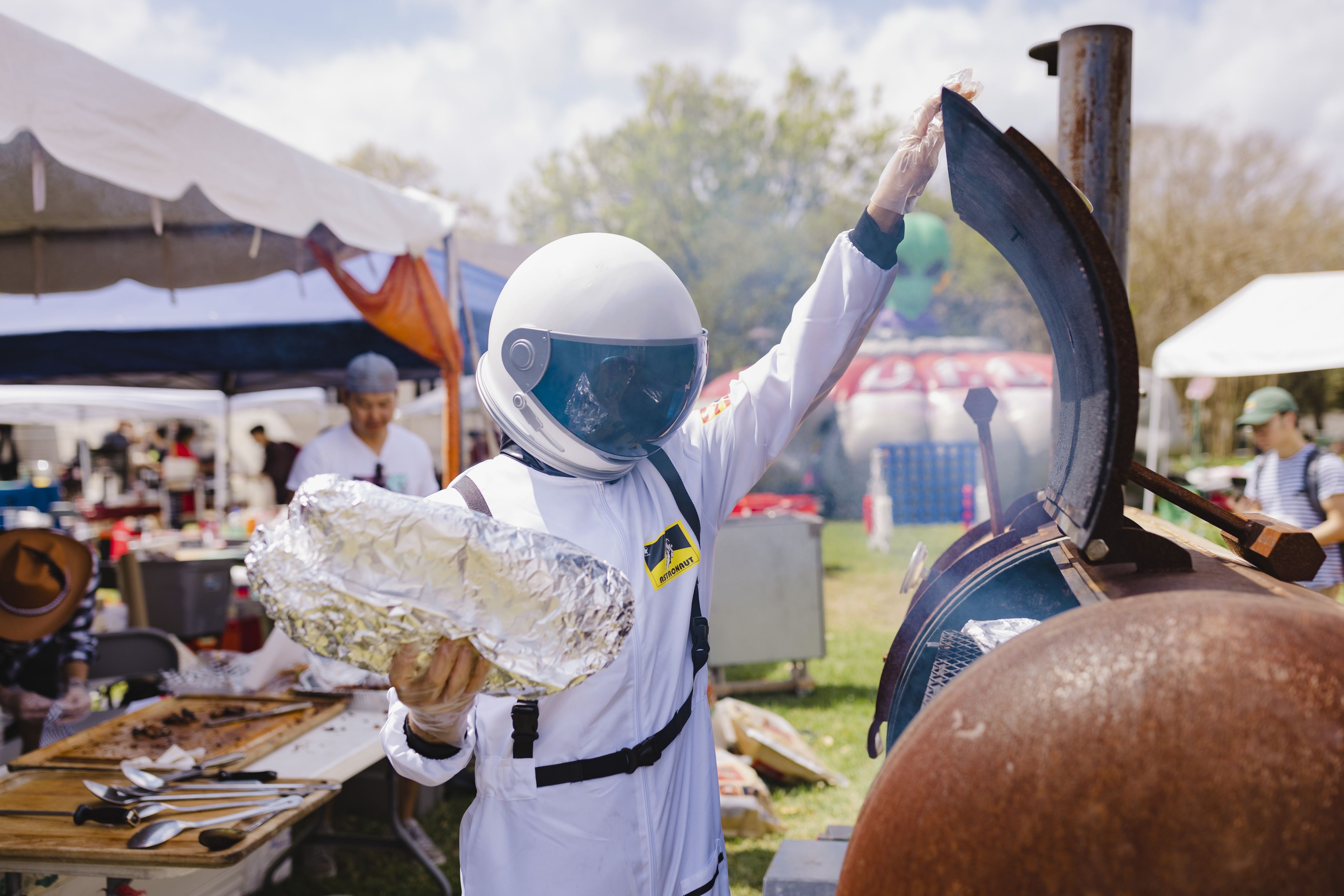 Student wearing an astronaut costume operates a smoker during the Wolffest competition.. 