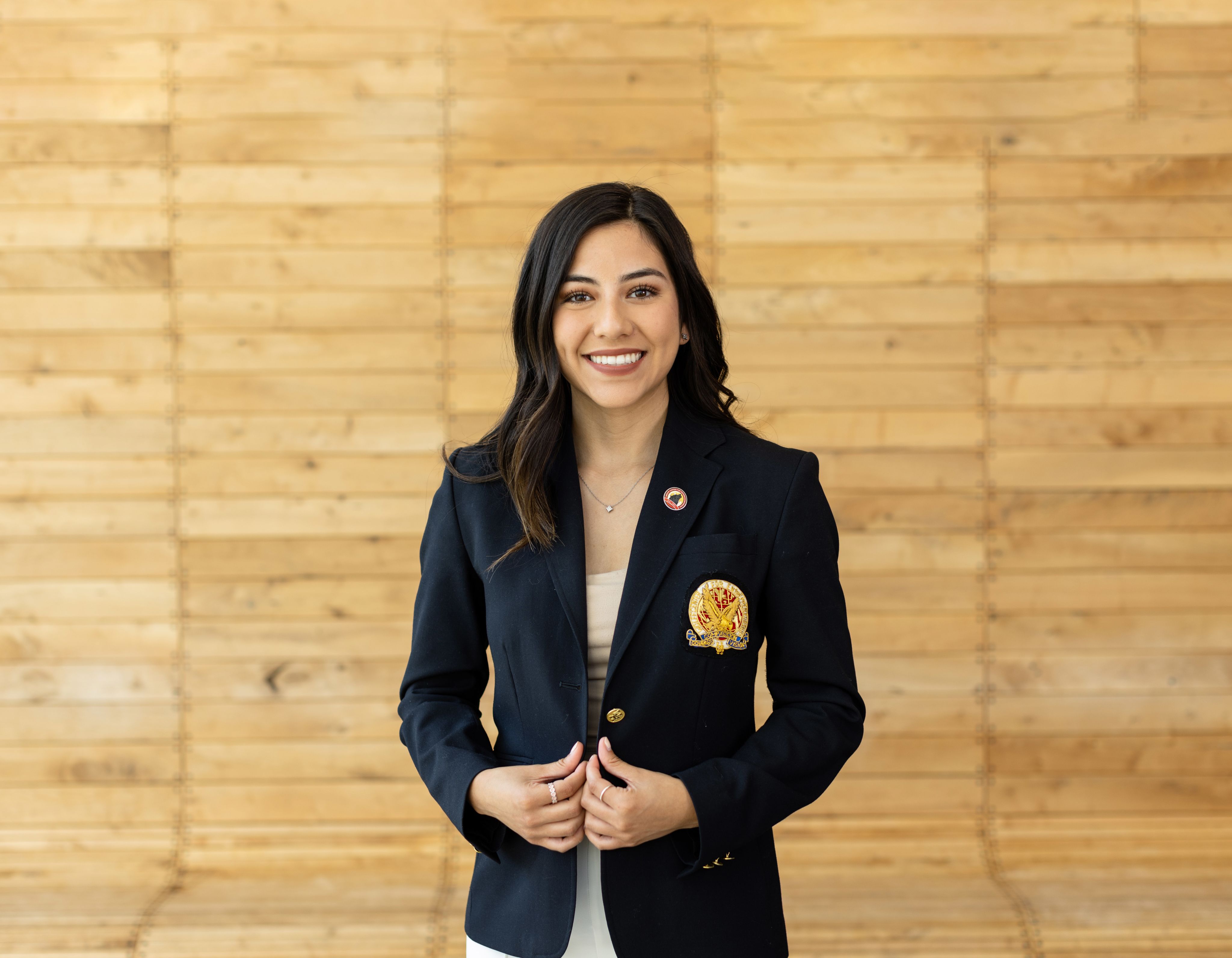 A smiling female student wears an honorary jacket.