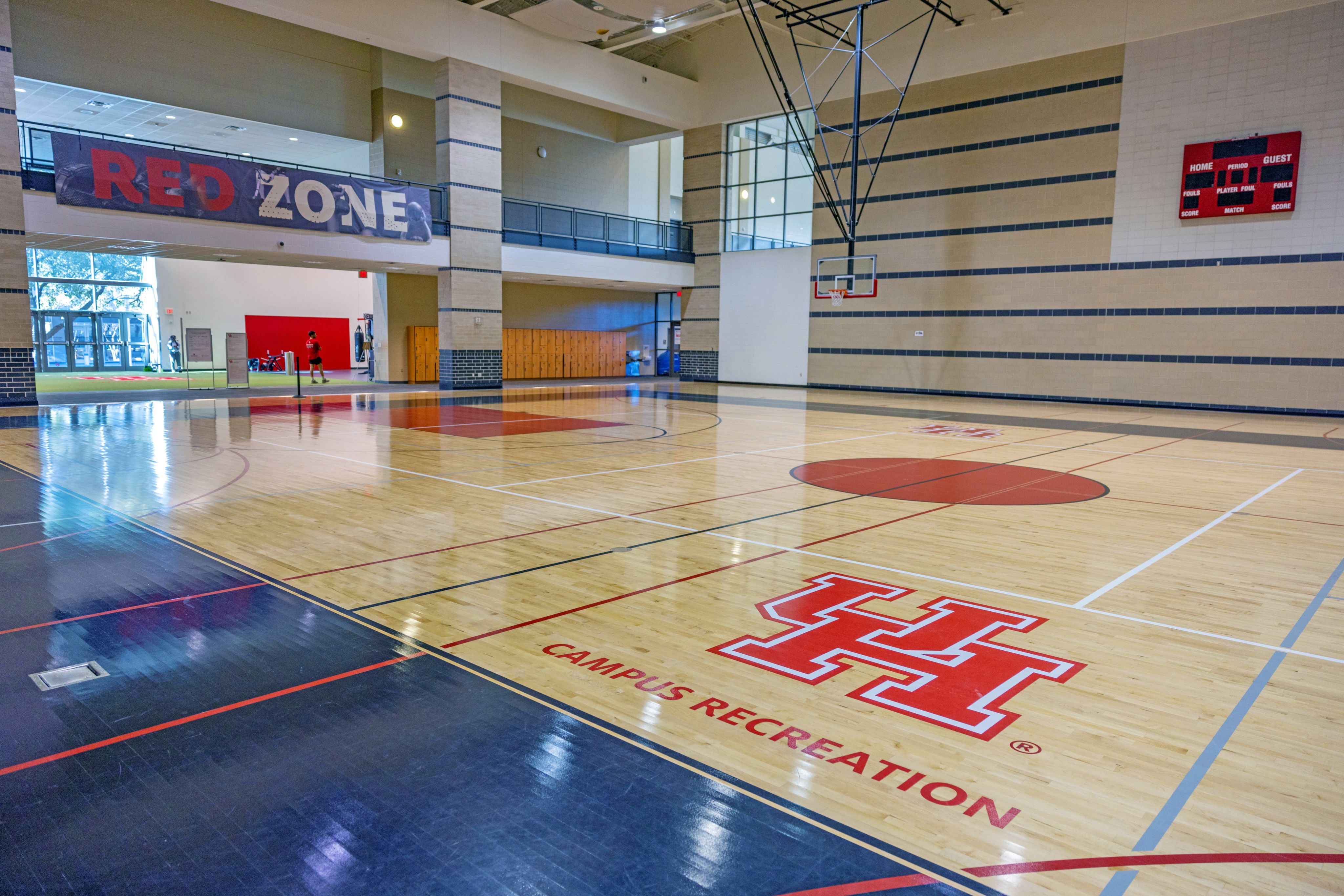 An empty basketball court with the UH logo on the floor at the Fitness Zone.