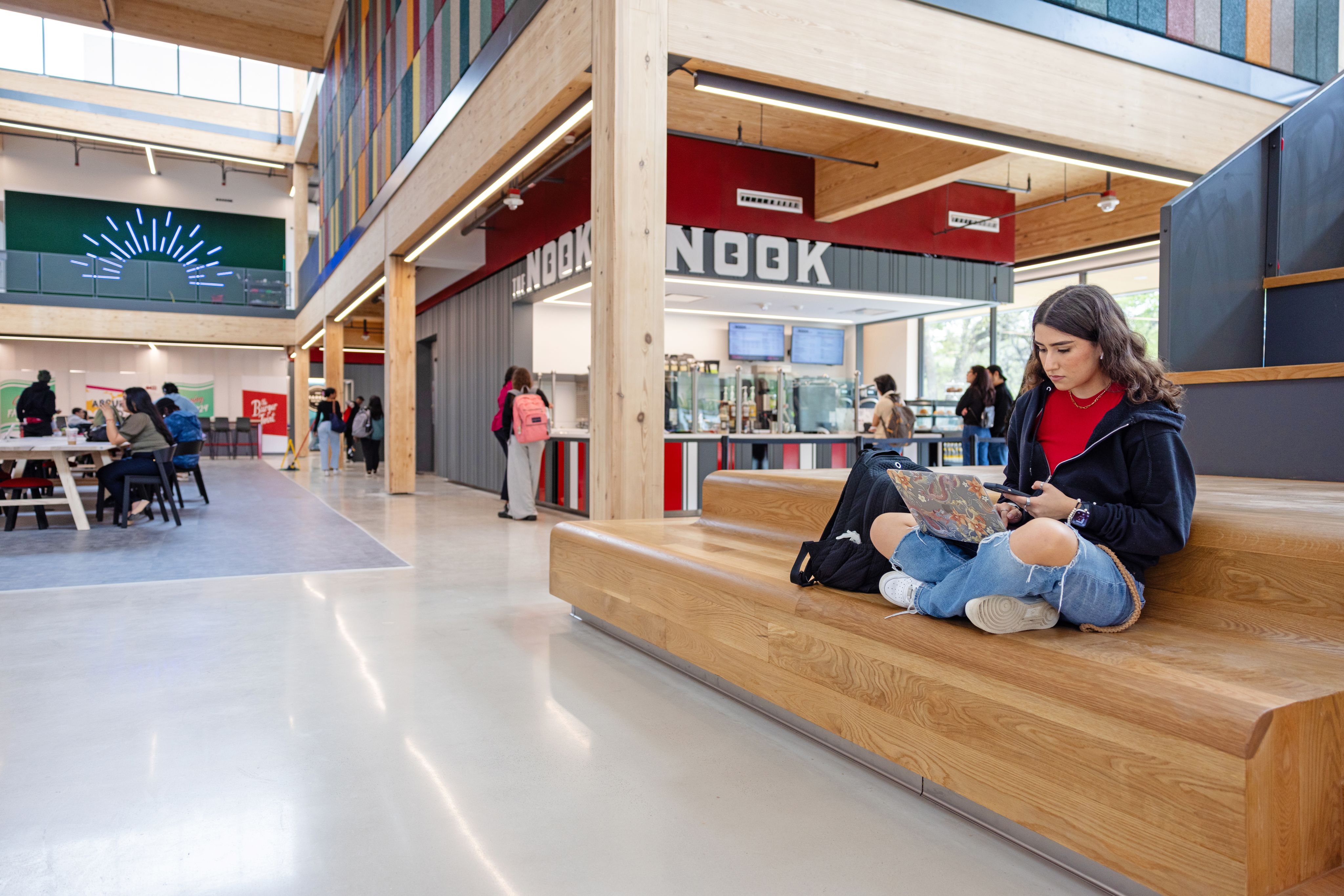 A female student sits working on her laptop on a bench in the RAD Center.