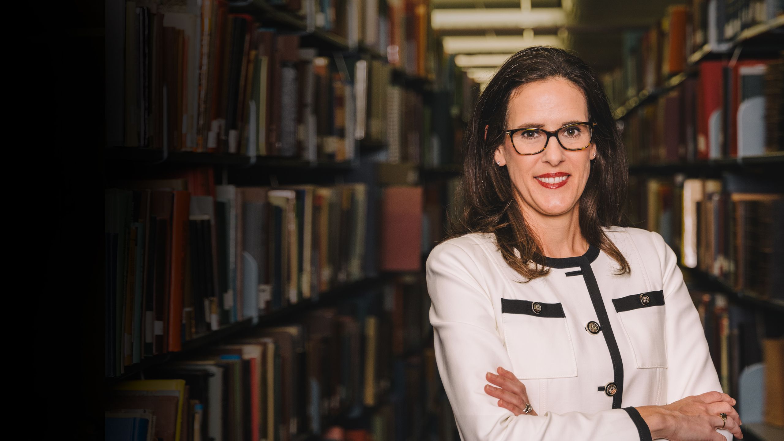 Portrait of Christina Gola, interim dean of libraries, standing in the library stacks.