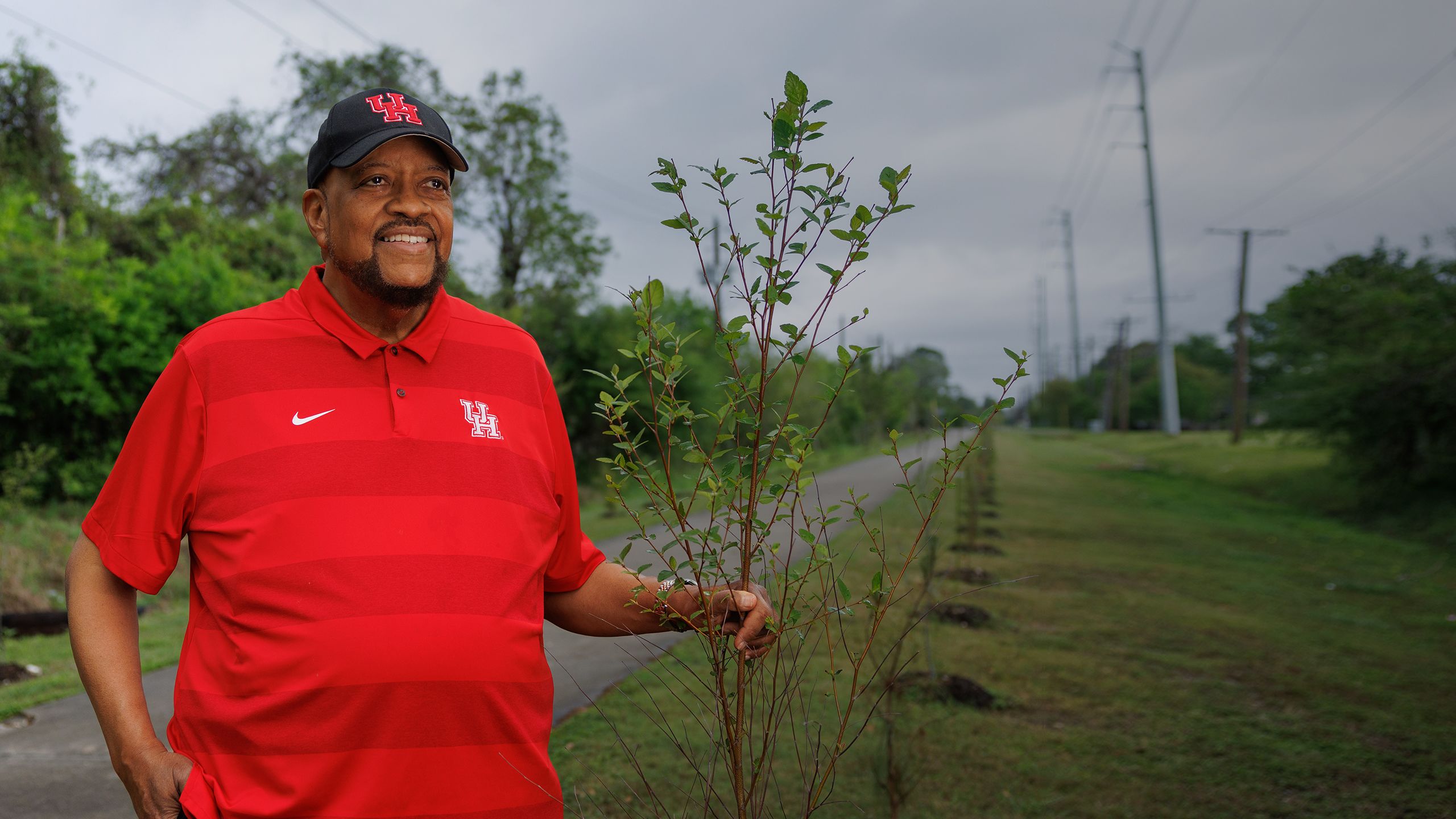 Elwyn Lee poses on the Columbia Tap Trail with one of the new tree saplings 