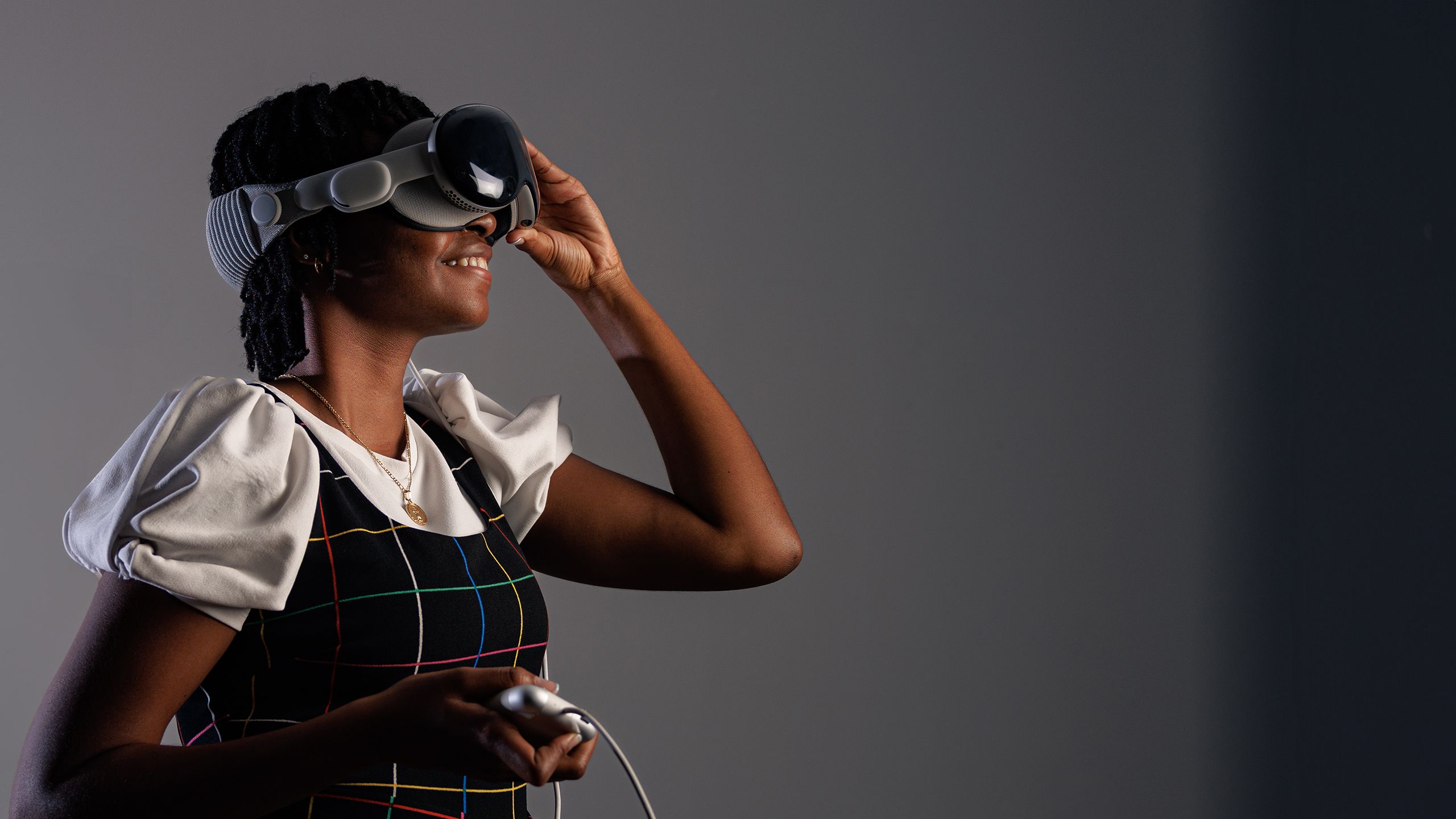 Abion Stevens smiles and holds her had up to her face to adjust a VR headset