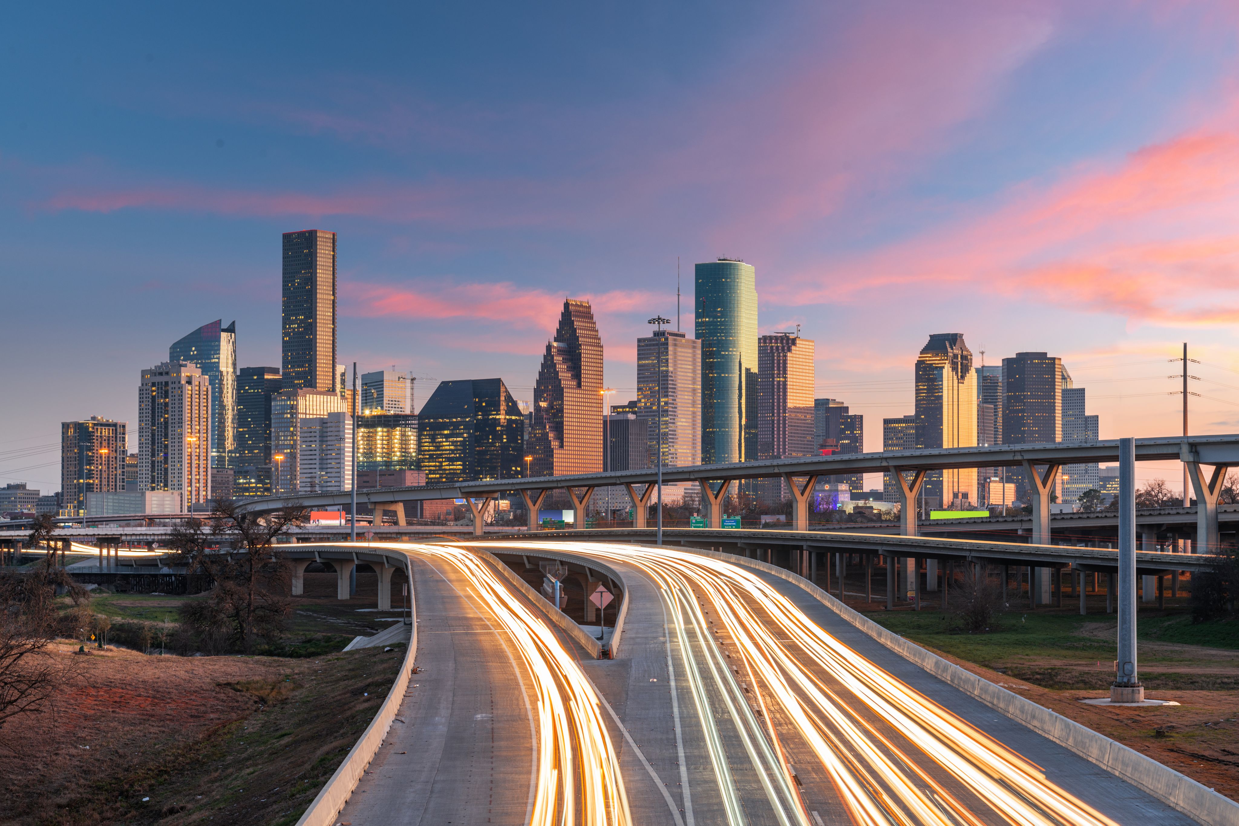 Photo of Houston city skyline and highway with pink sunset in background
