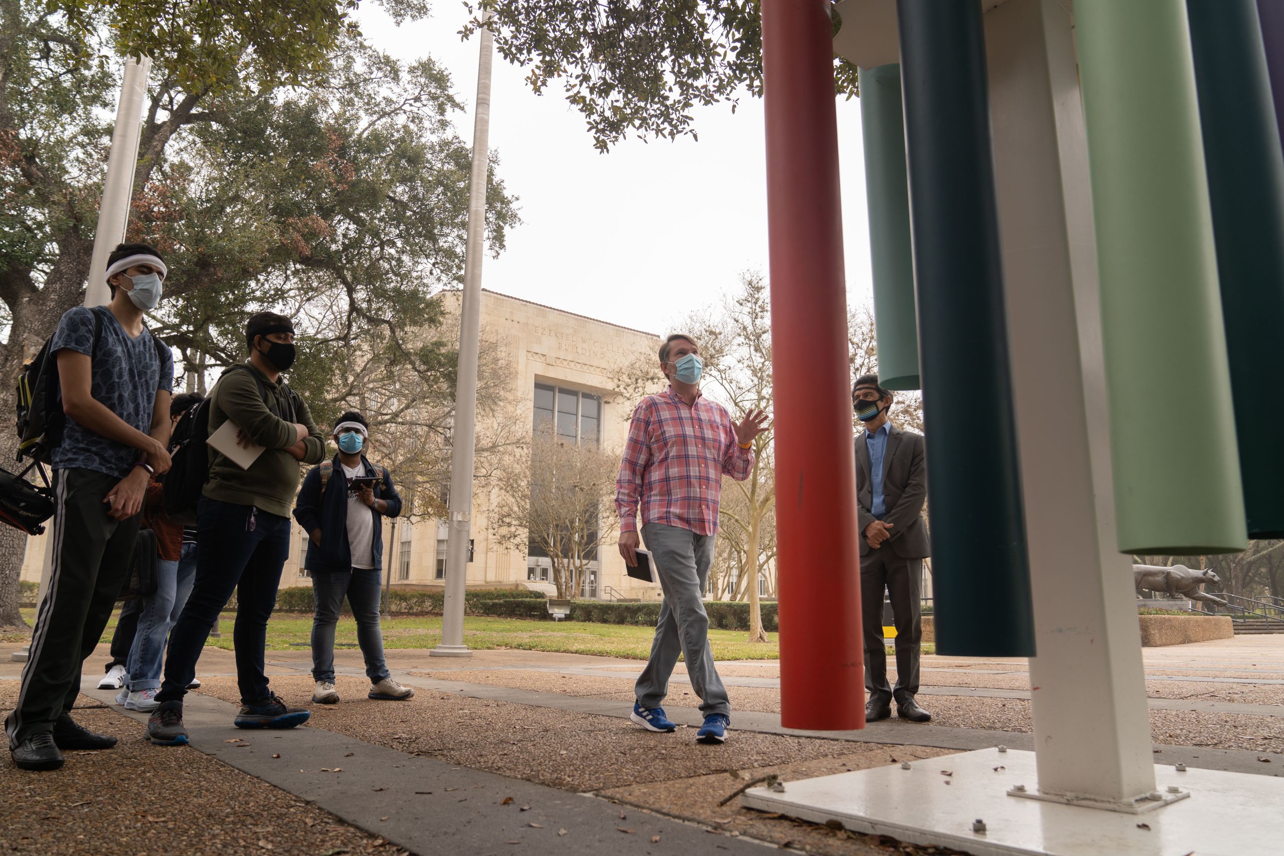 Public art UHS curator Mike Guidry talks to UH engineering students about "Untitled (Wind Chimes)," (2014) by Sam Falls during a tour of "Color Field."