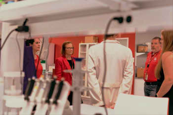 Photograph of people taken through white lab shelves. 