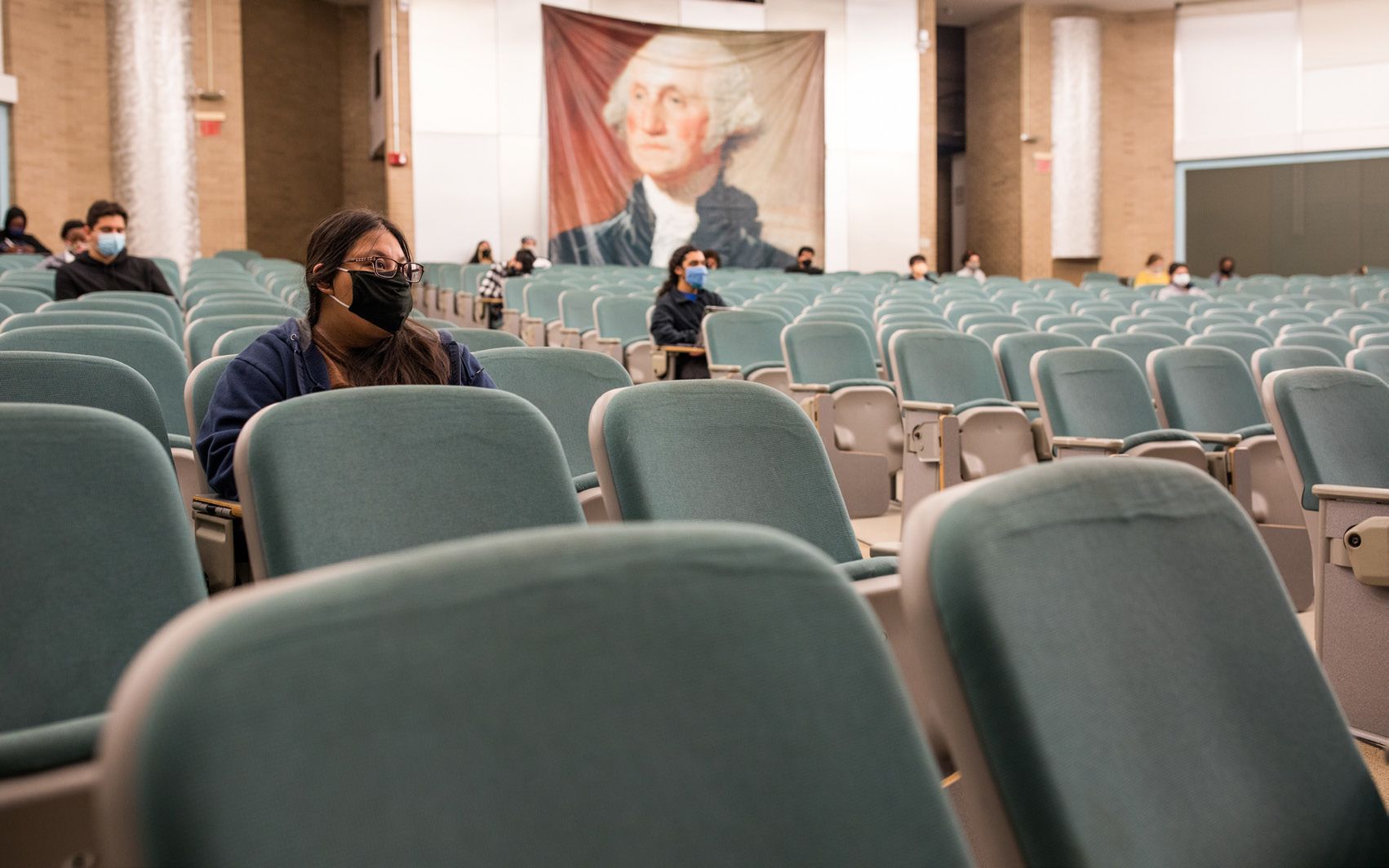 A few people sitting in a large classroom