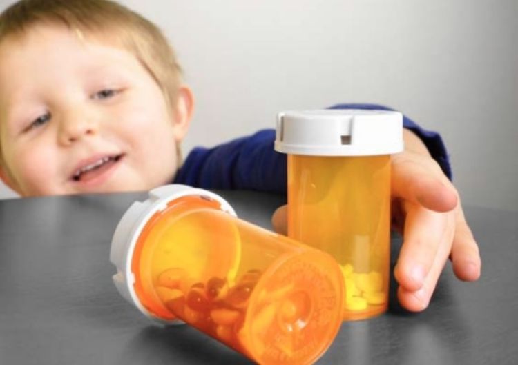 A kid reaching out to a bottle of pills