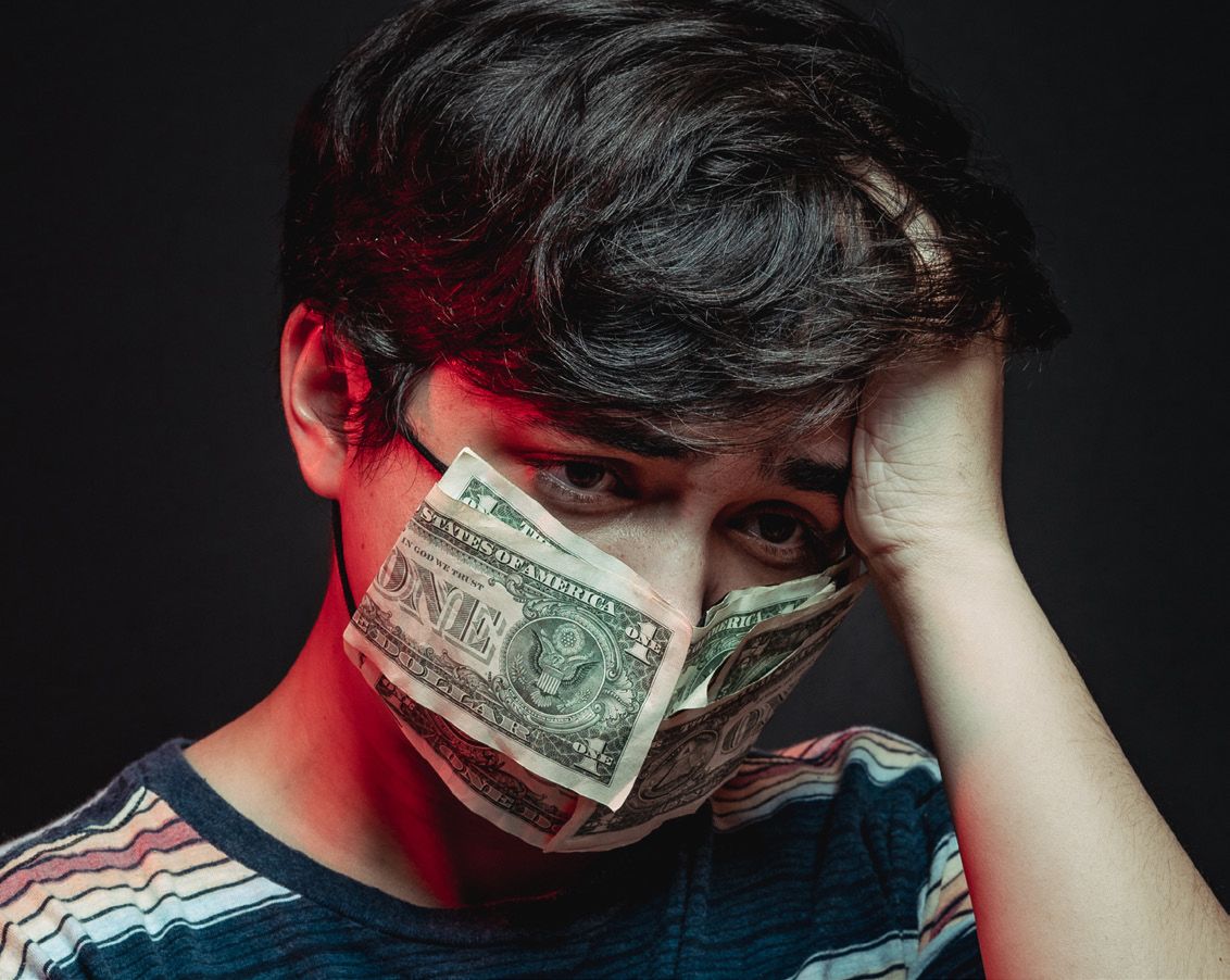 A person is feeling anxious and has a face mask covered with money.