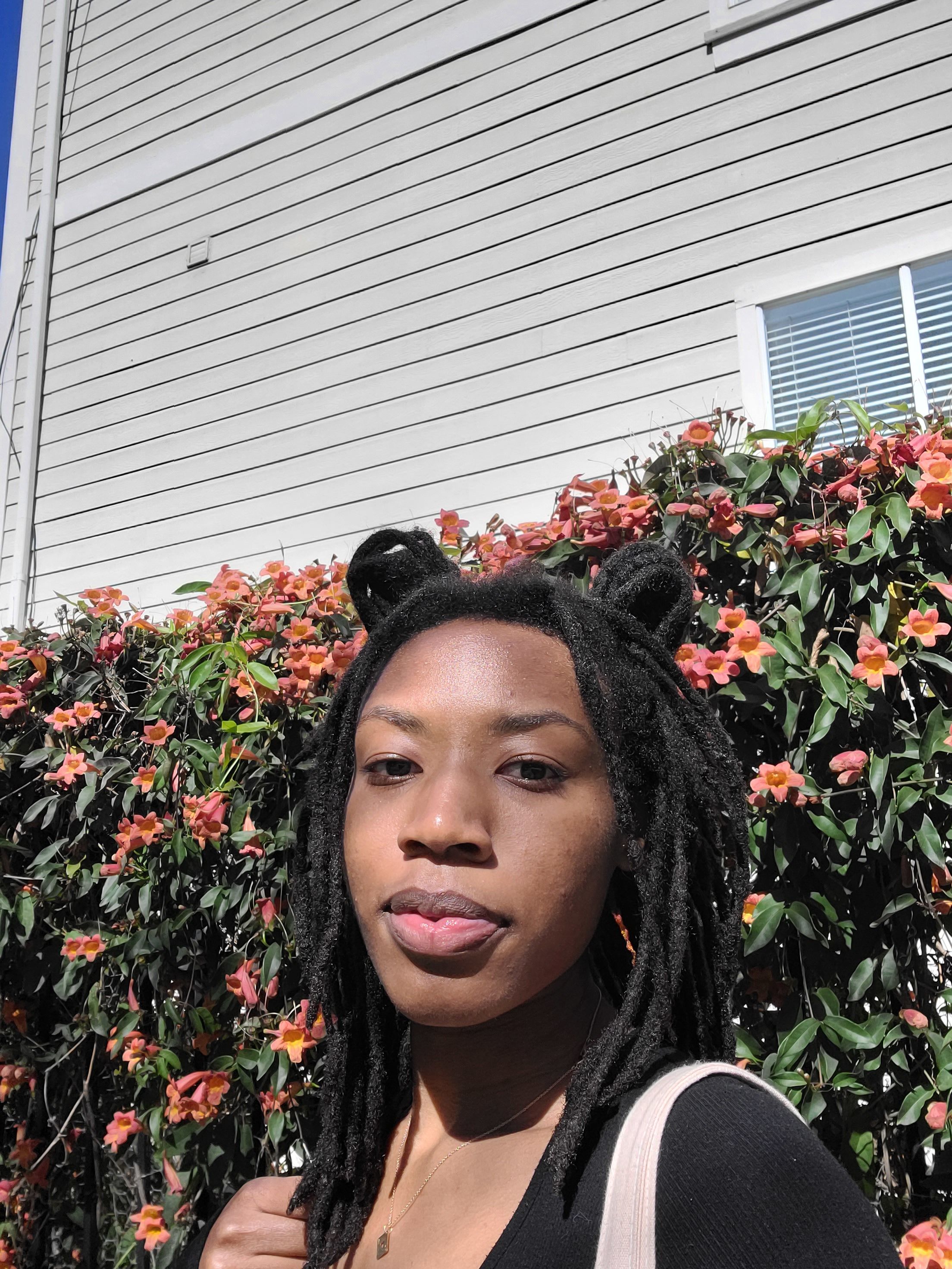 African American woman standing in front of flowers, bush