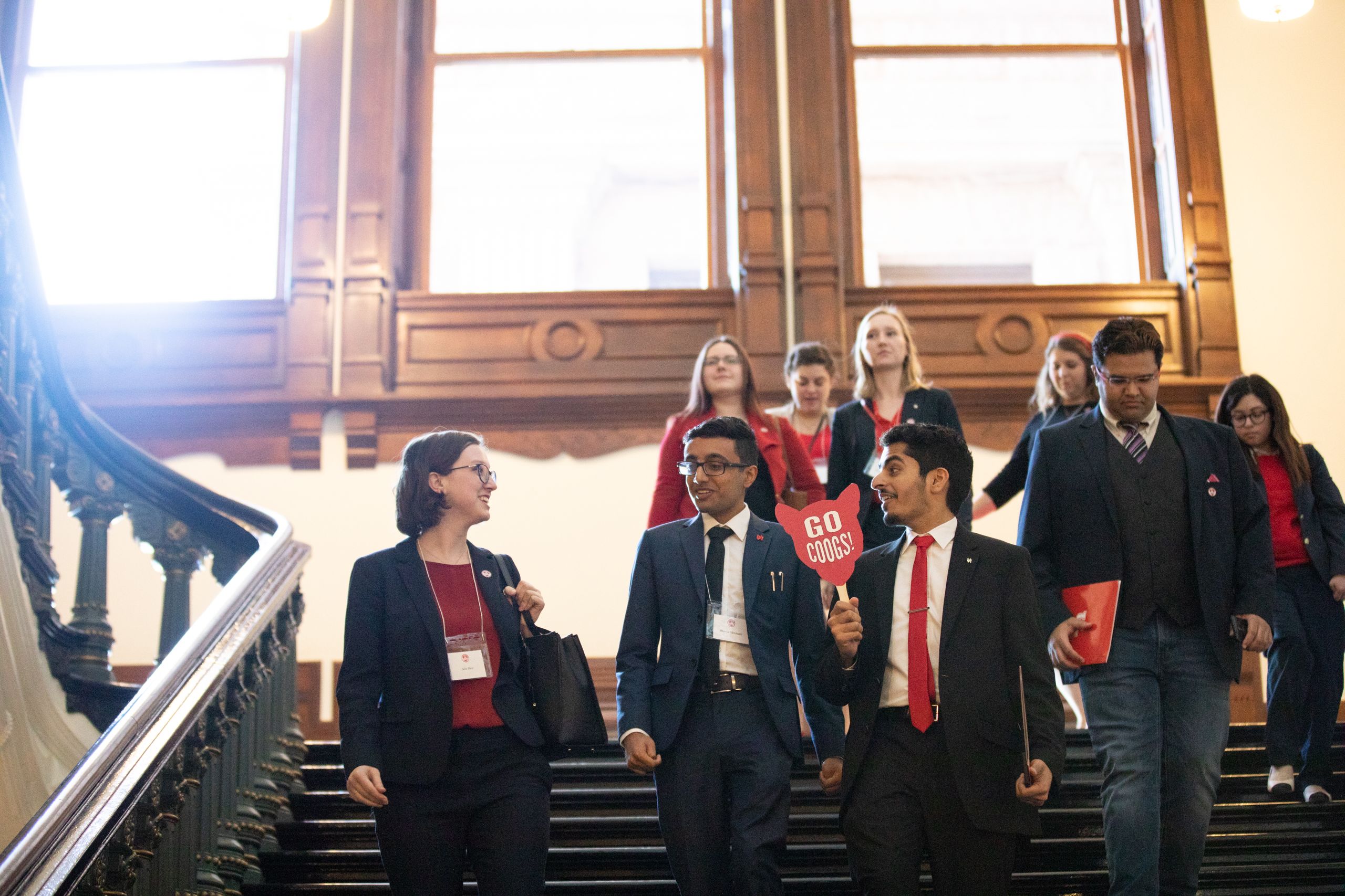 Group of nine people walks down large staircase in Texas capitol building.