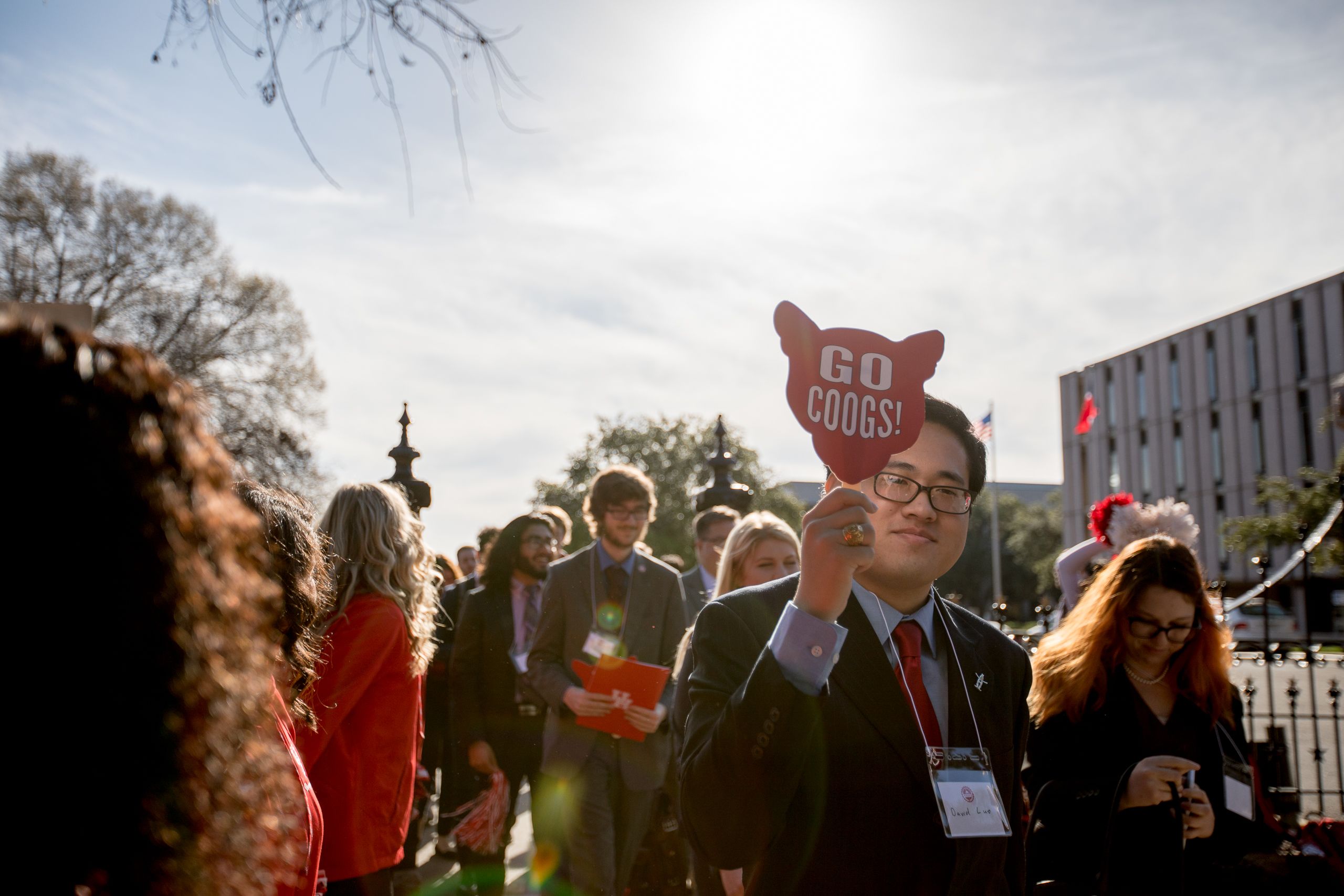 Student carrying "Go Coogs!" sign as he walks twoard capitol building