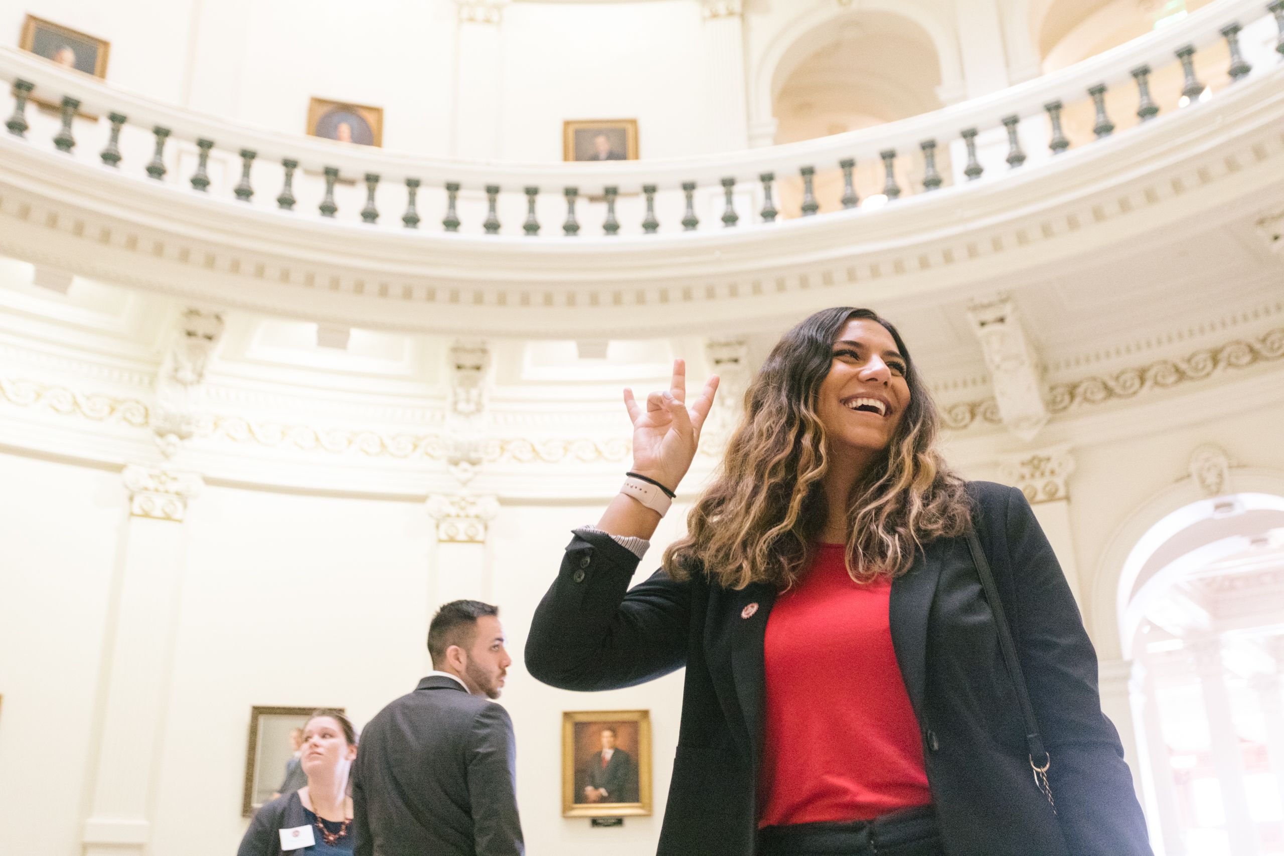 student holding up the "Go Coogs" hand sign in the Capitol rotunda.