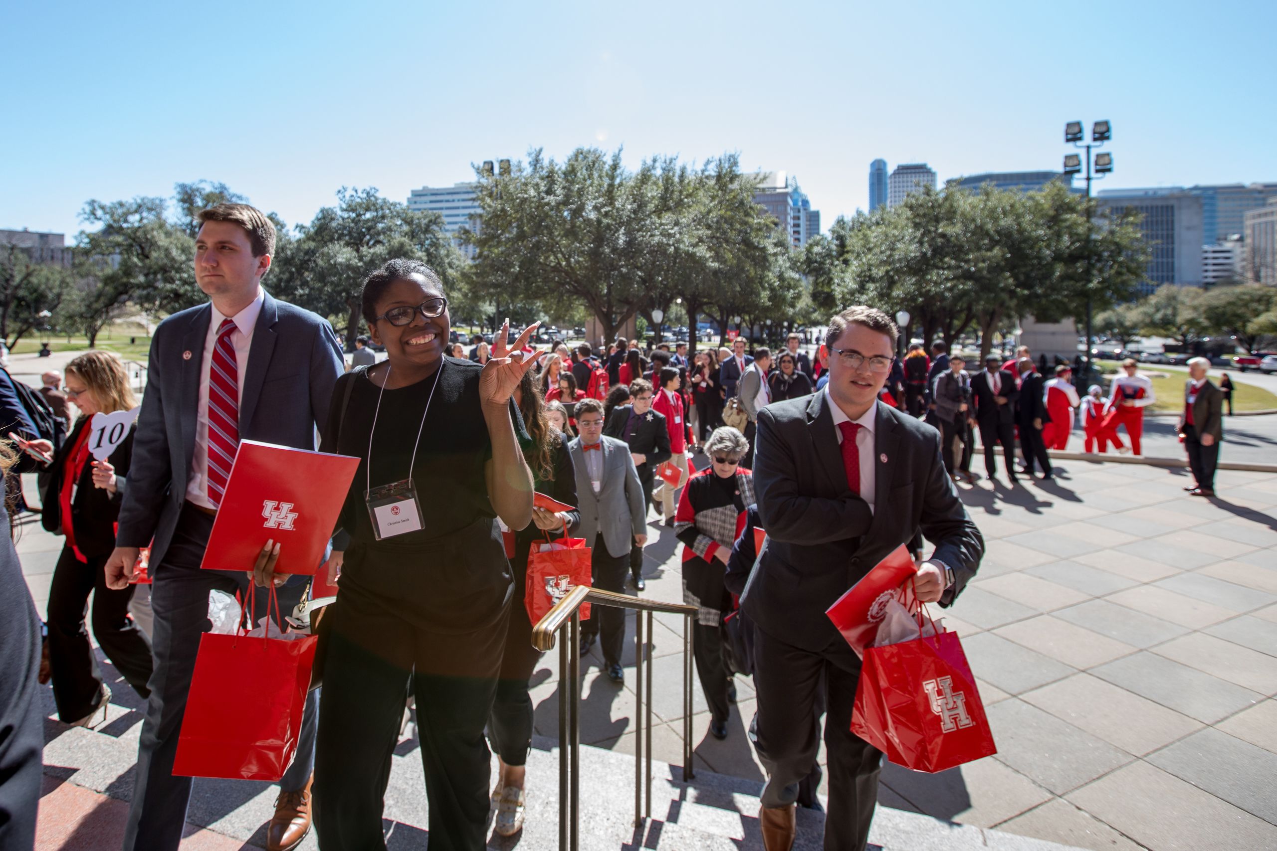 Group of students walking up steps, hold bags with UH stuff.
