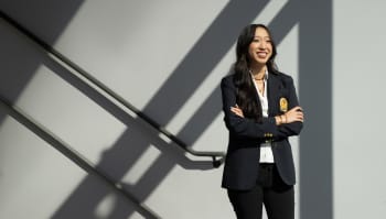 This is a photo of UH Senior Evie Vuong. She is standing in a stairwell with arms folded.